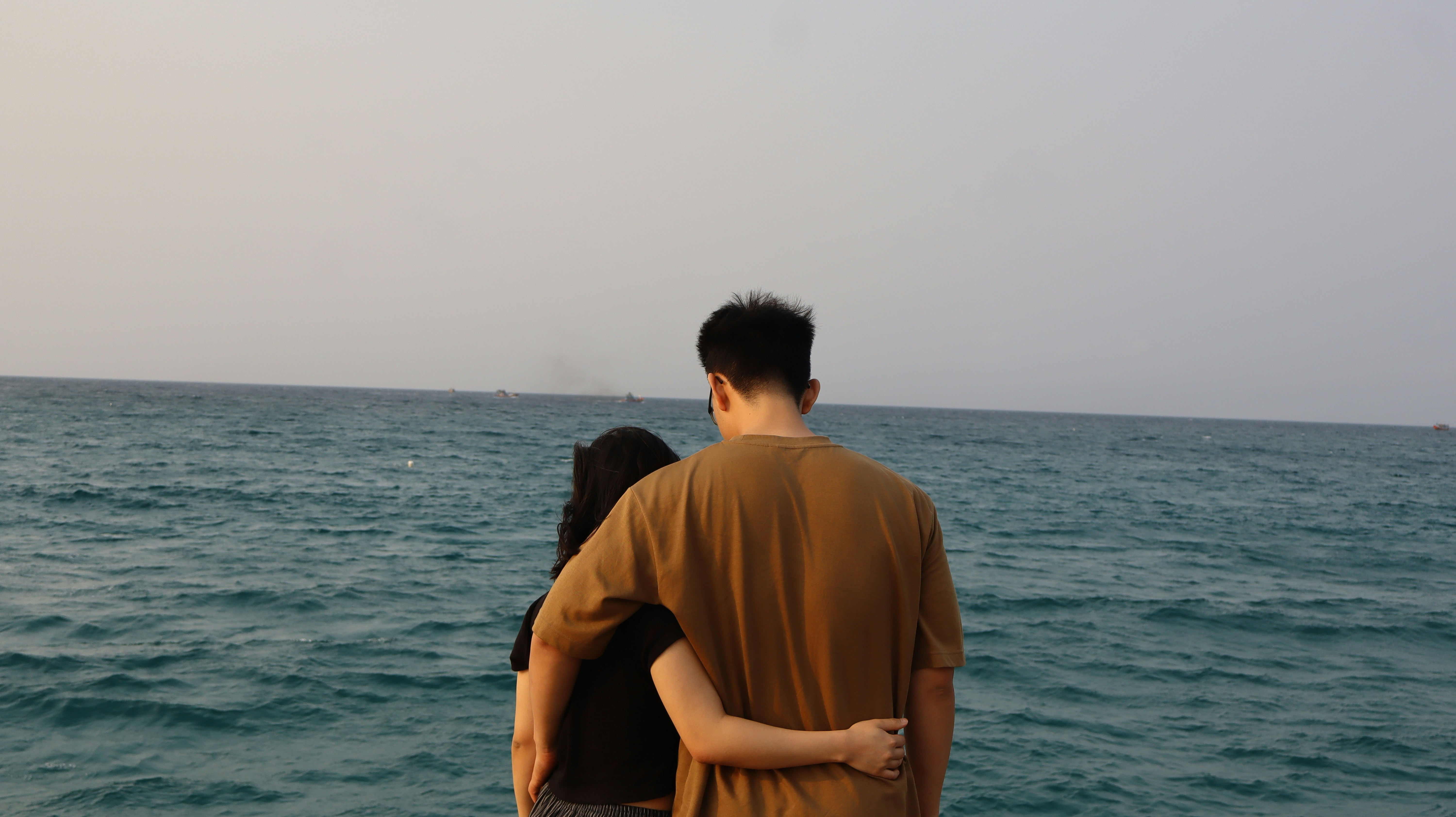 Pareja abrazándose junto al mar al anochecer