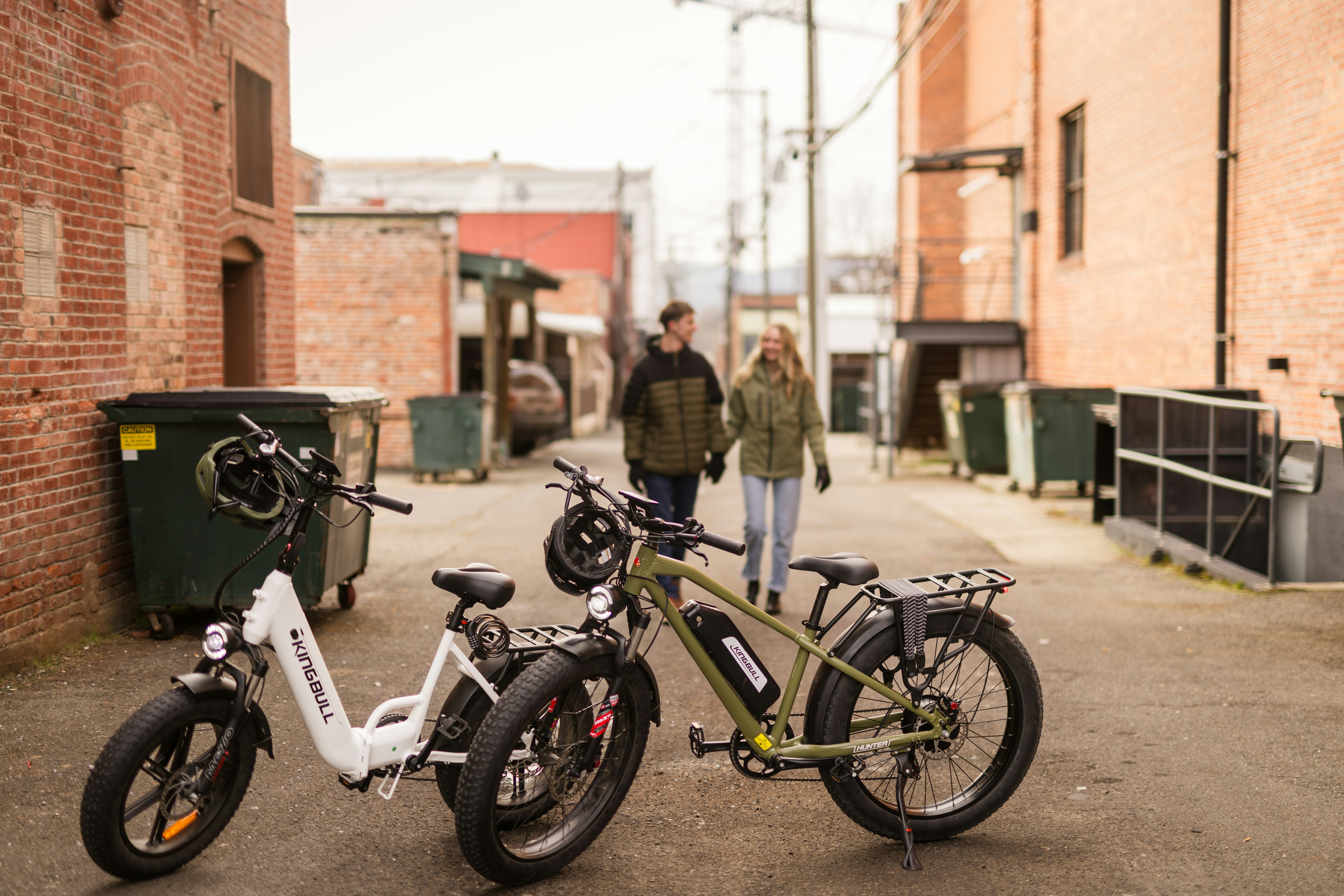 Casal passando por bicicletas elétricas em um beco