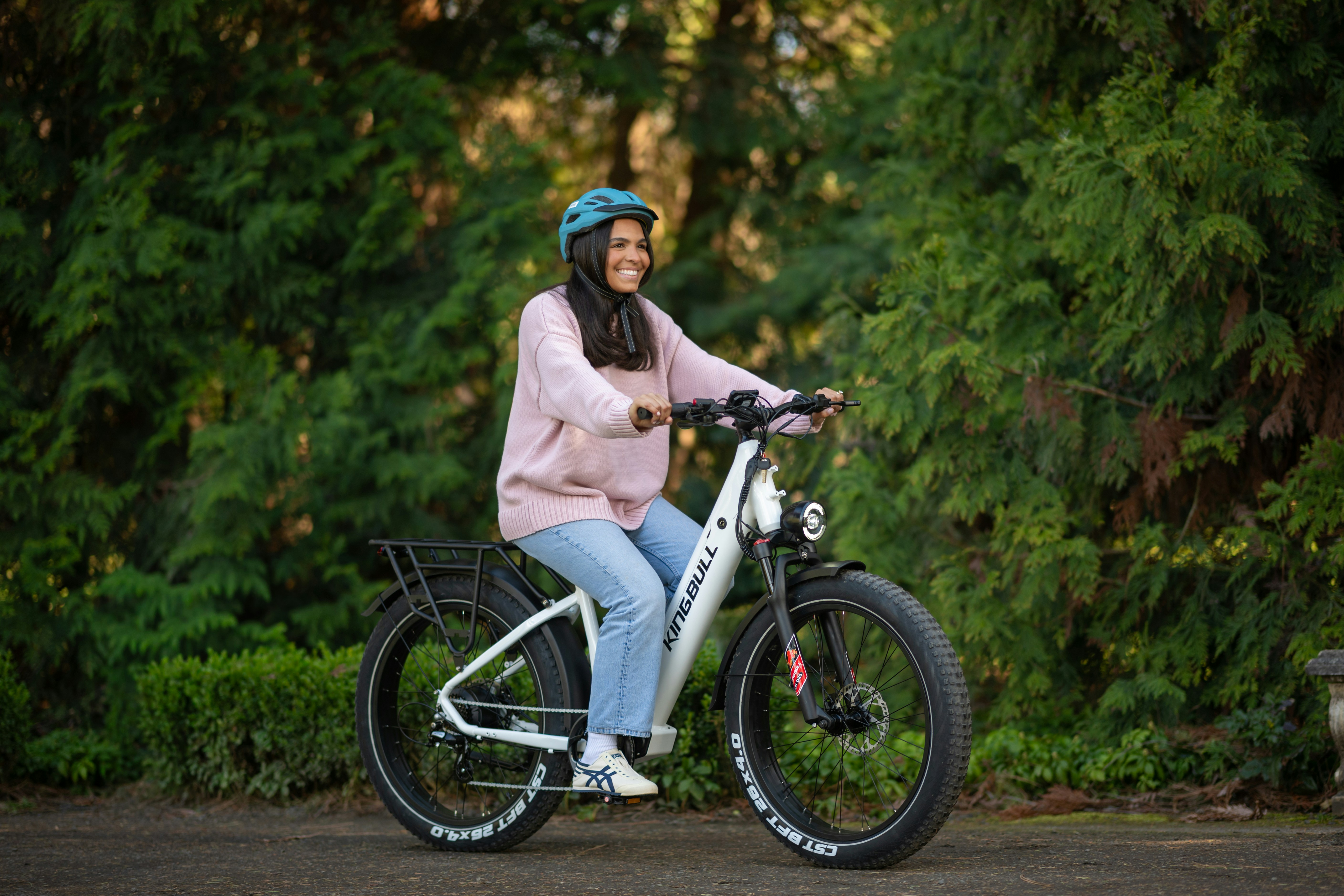 Jovem mulher andando de bicicleta elétrica branca ao ar livre.