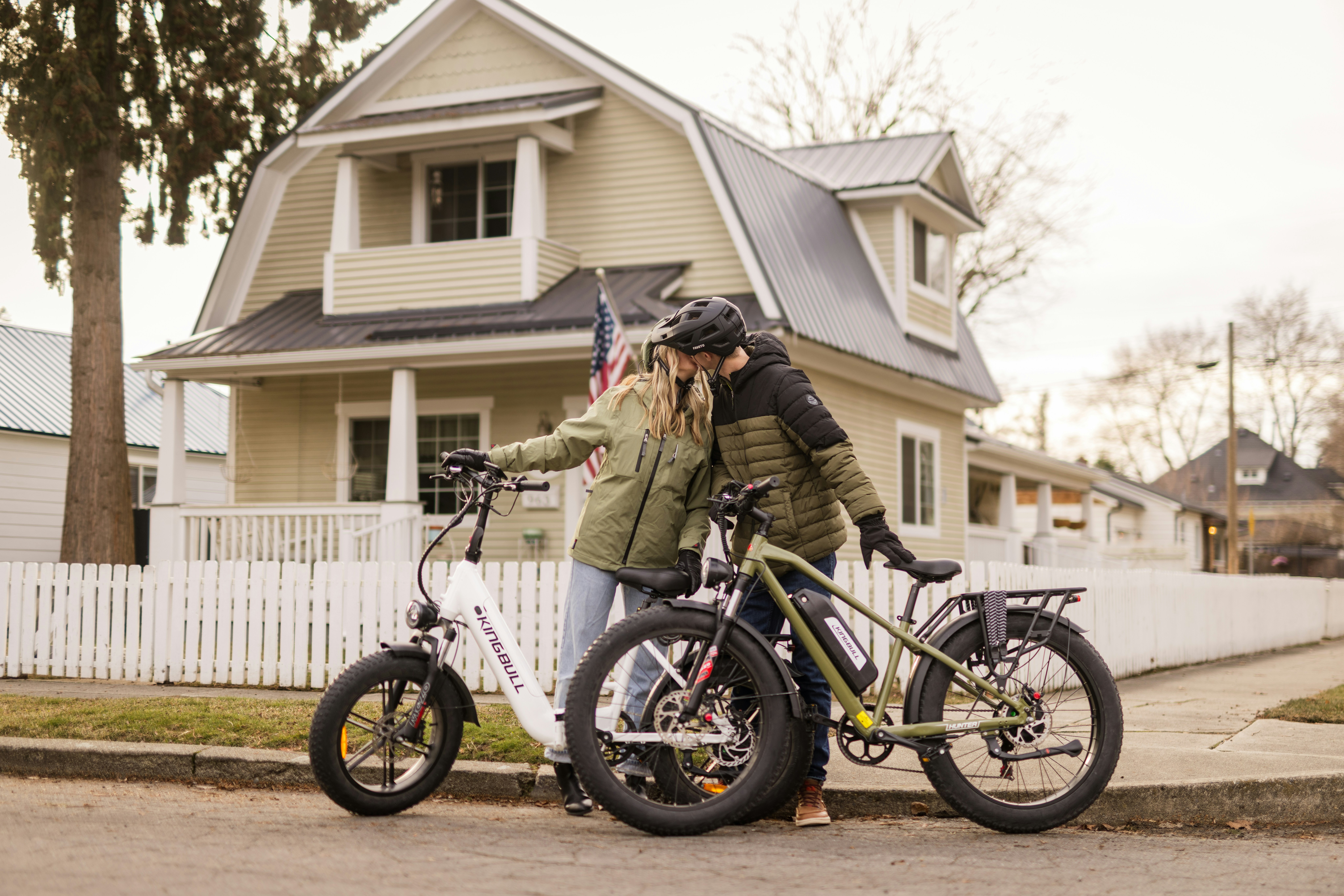 Casal se beijando com bicicletas em frente a uma casa