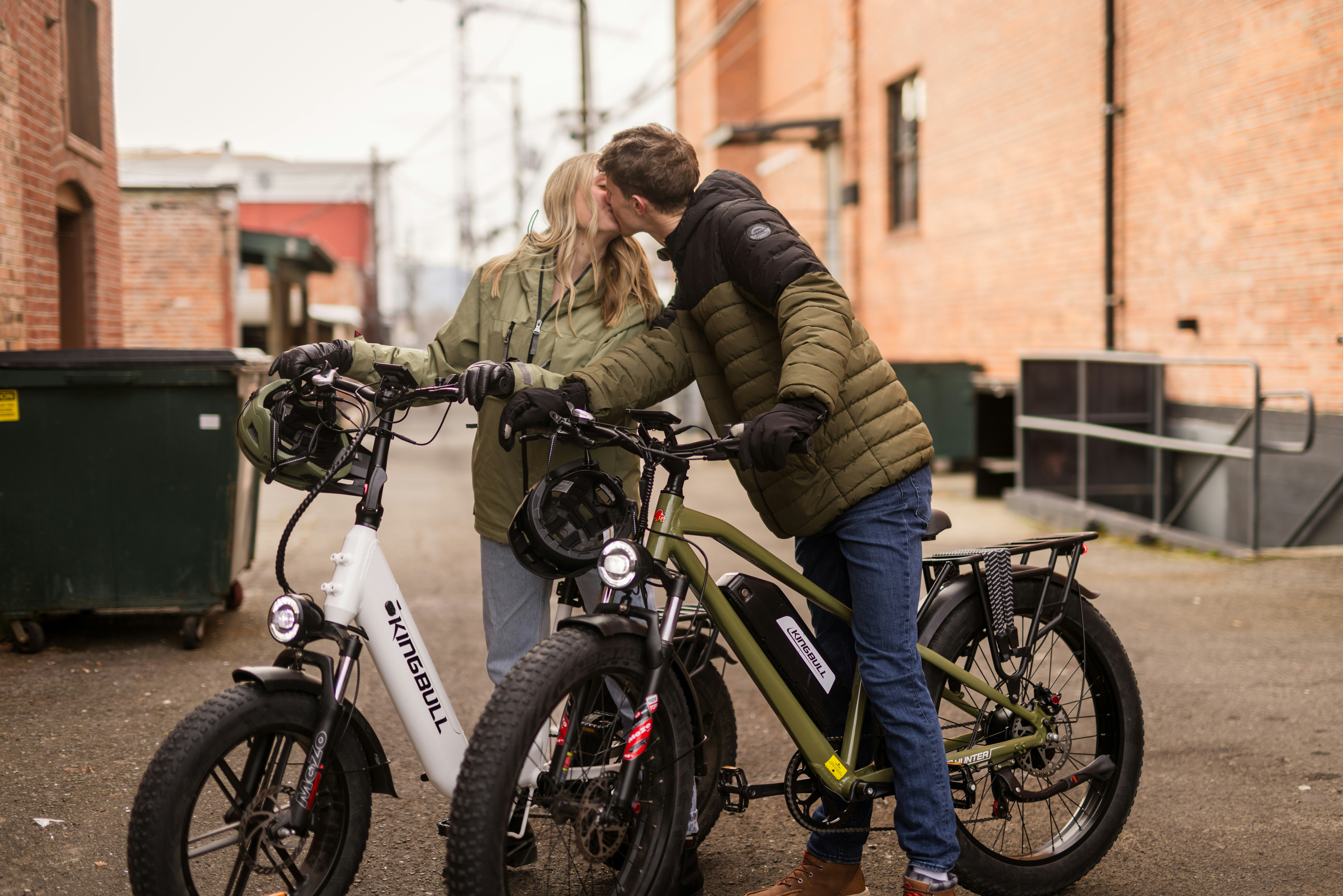 Casal se beijando entre duas bicicletas elétricas