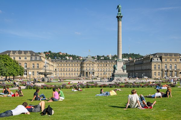 People relaxing on grass in front of a grand palace — Stuttgart, Germany