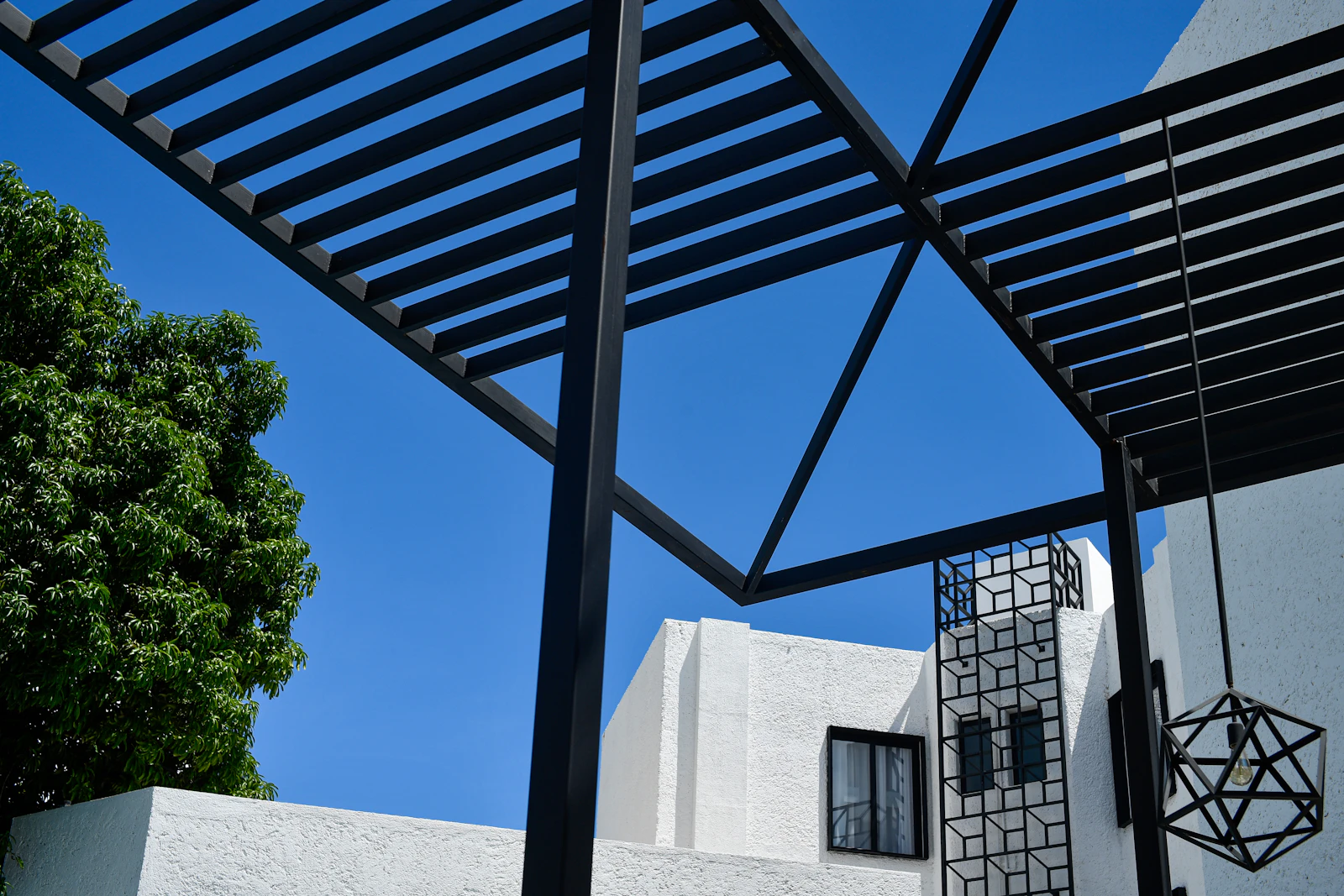 Referencia visual: pérgola negra de diseño contemporáneo bajo cielo azul