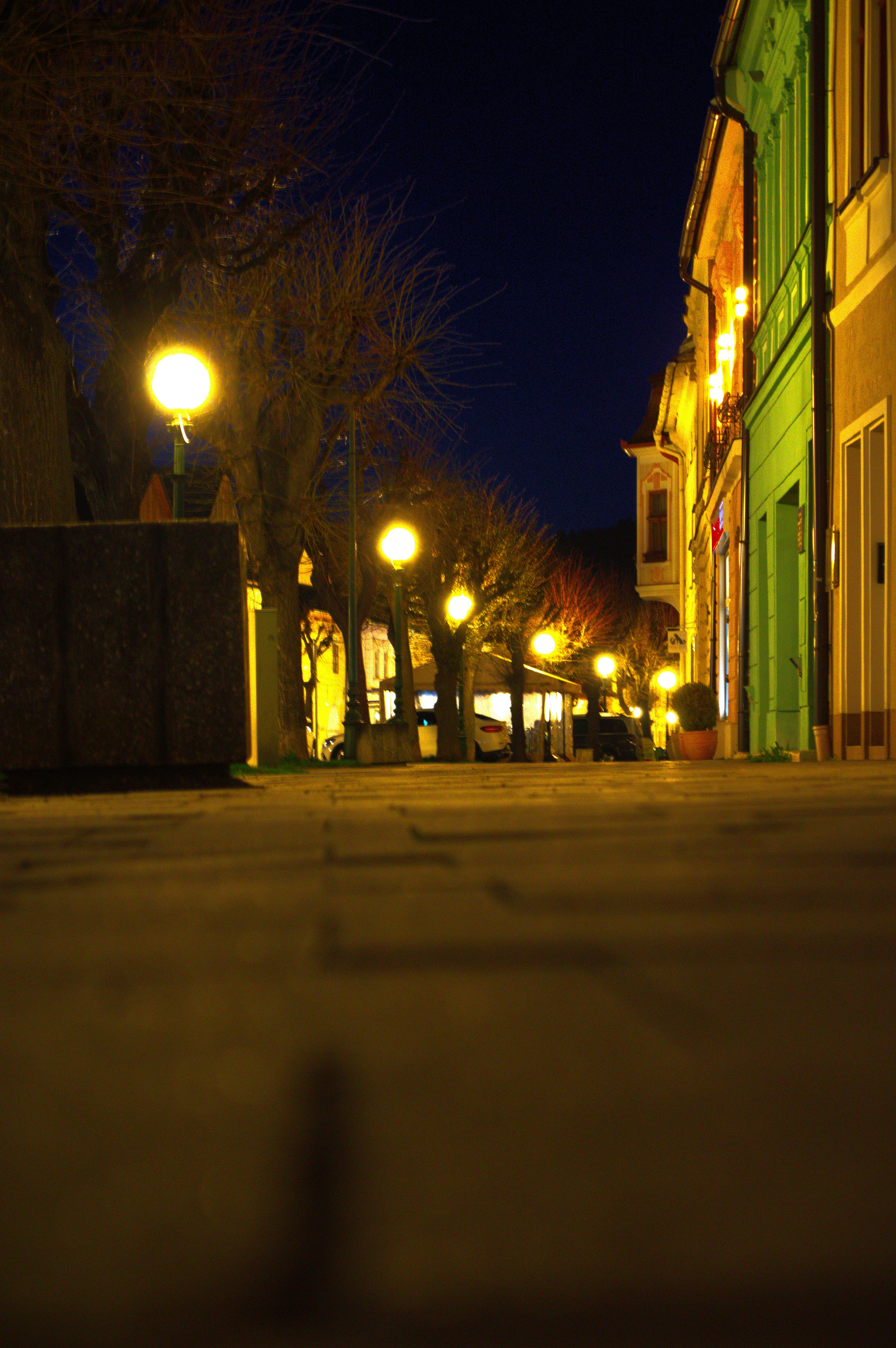 Postes de luz iluminam um caminho de paralelepípedo à noite