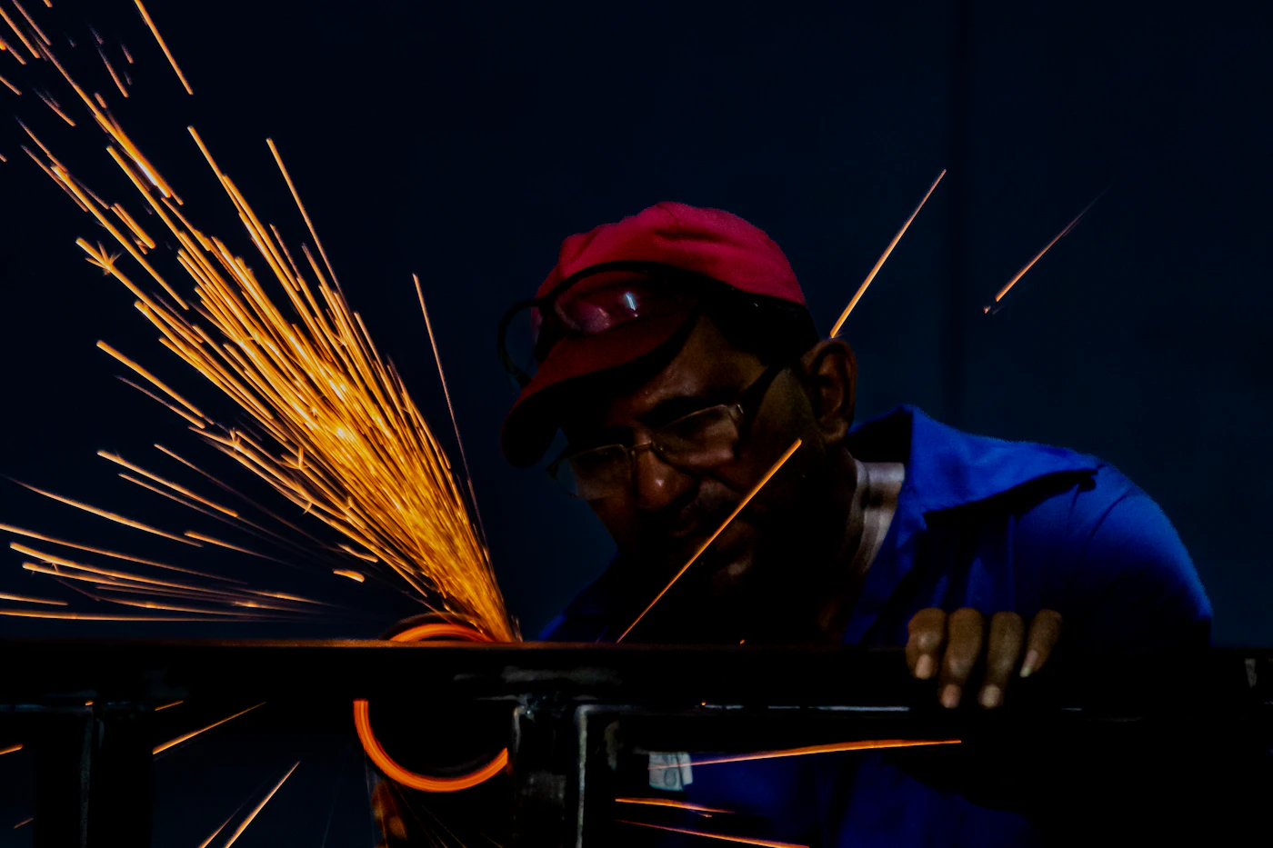 Sparks flying while a worker grinds metal, showing the need for eye and face protection