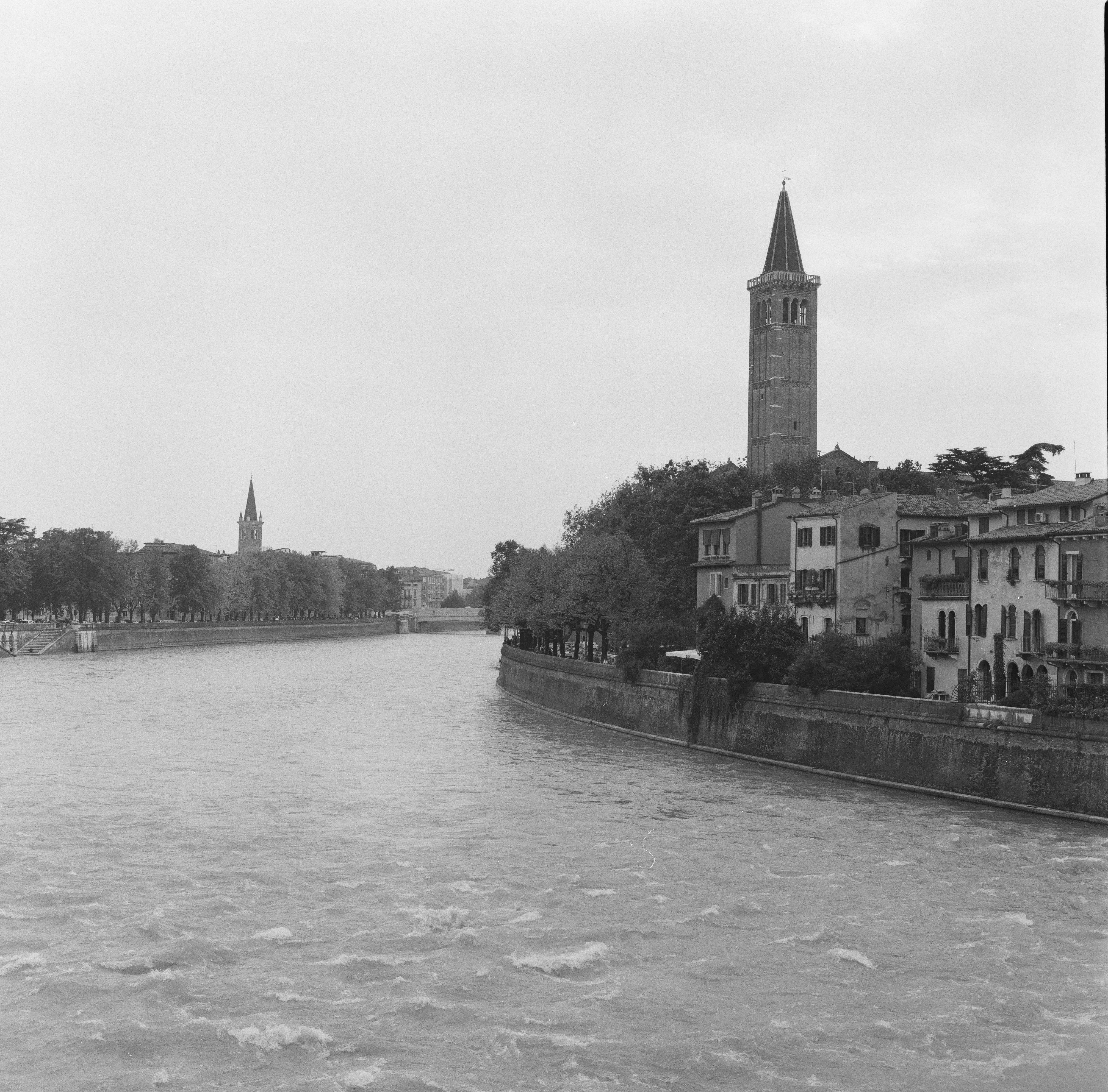 River flows past historic buildings and a prominent bell tower.