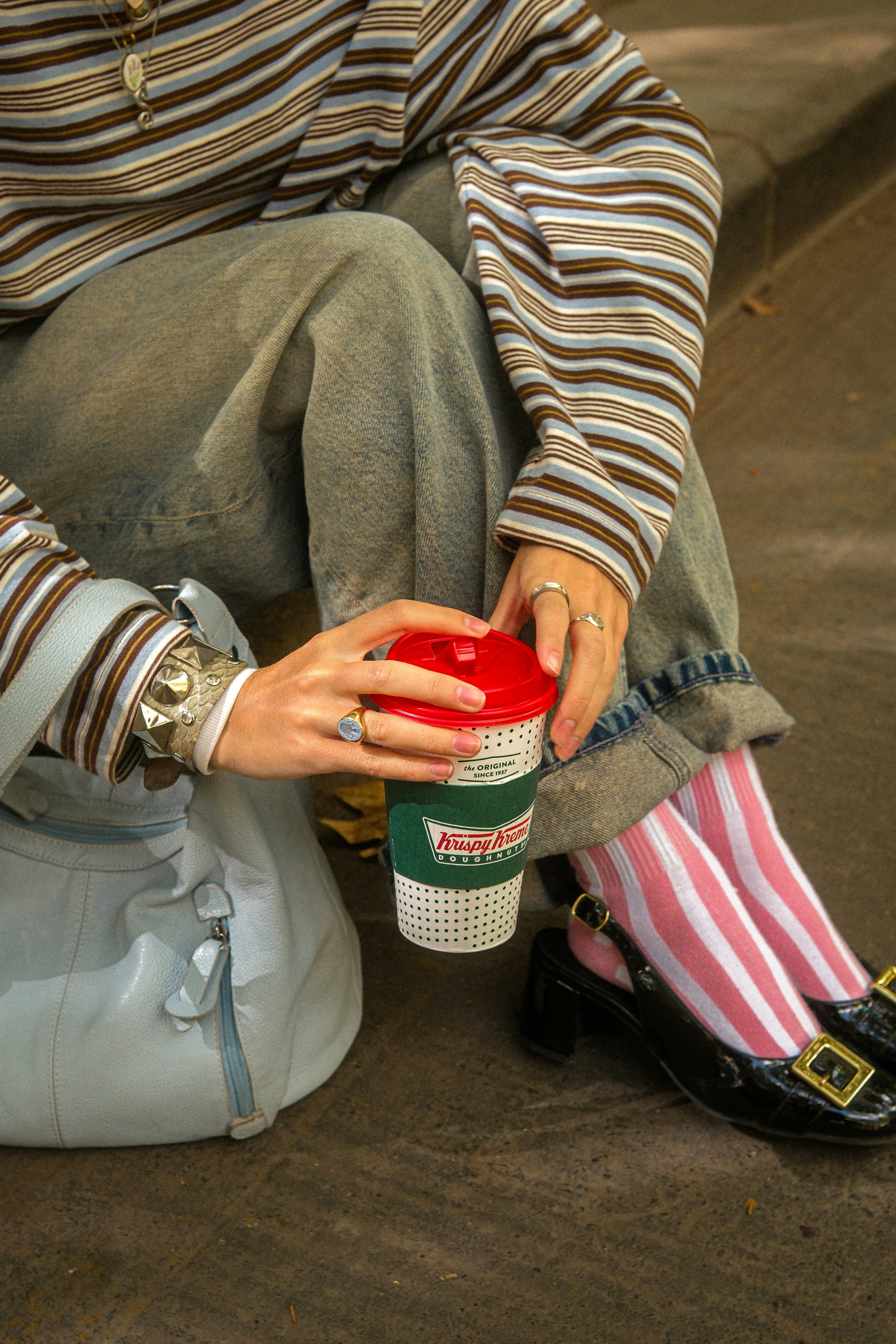 Person, die eine Kaffeetasse mit gestreiften Socken hält.