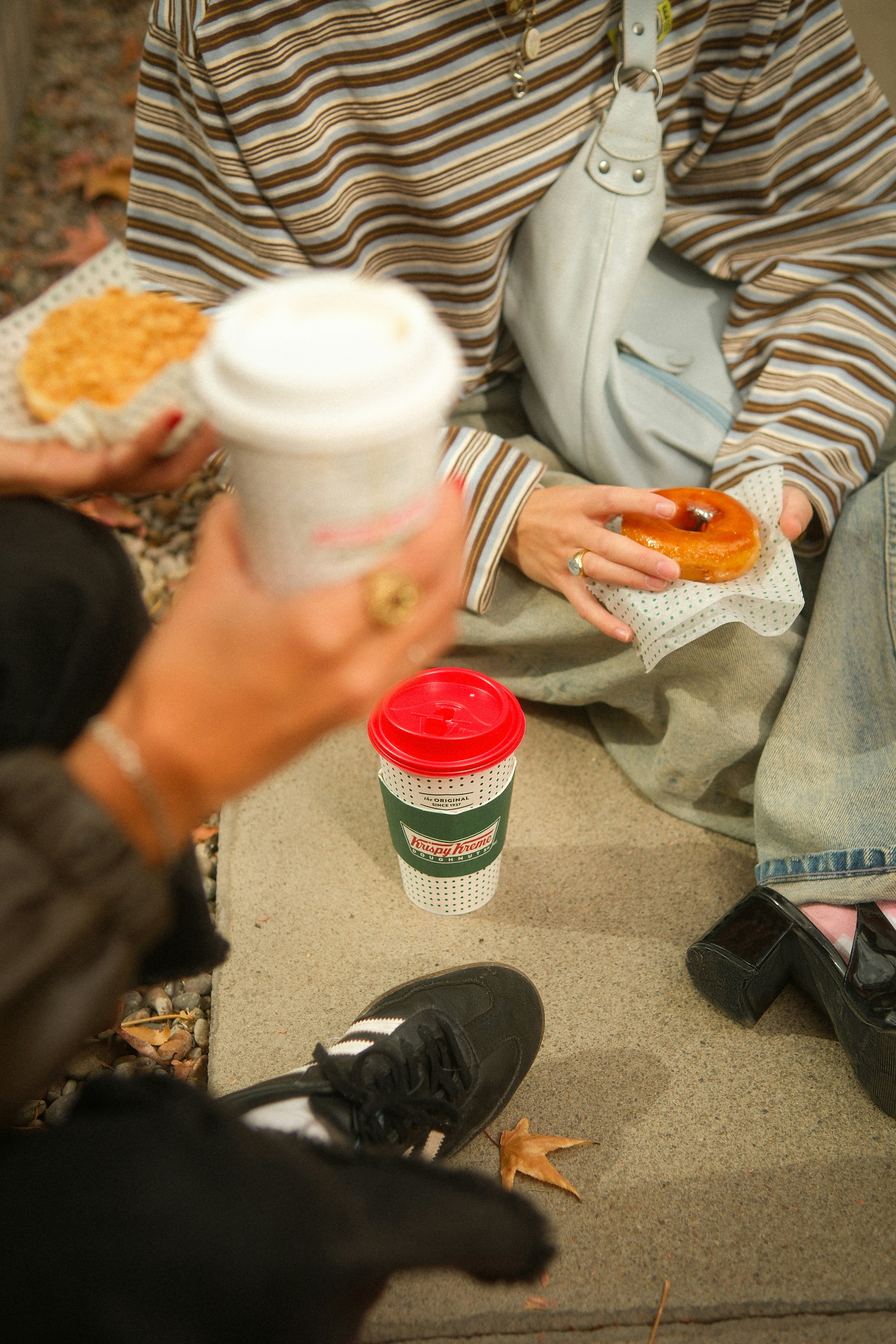 People holding coffee cups and donuts outdoors
