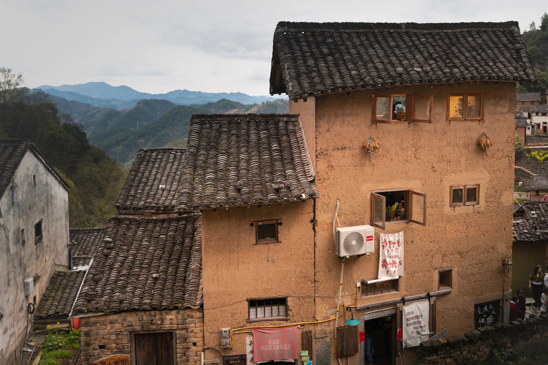Tall ochre earthen-walled houses with gray tile roofs in a mountain village