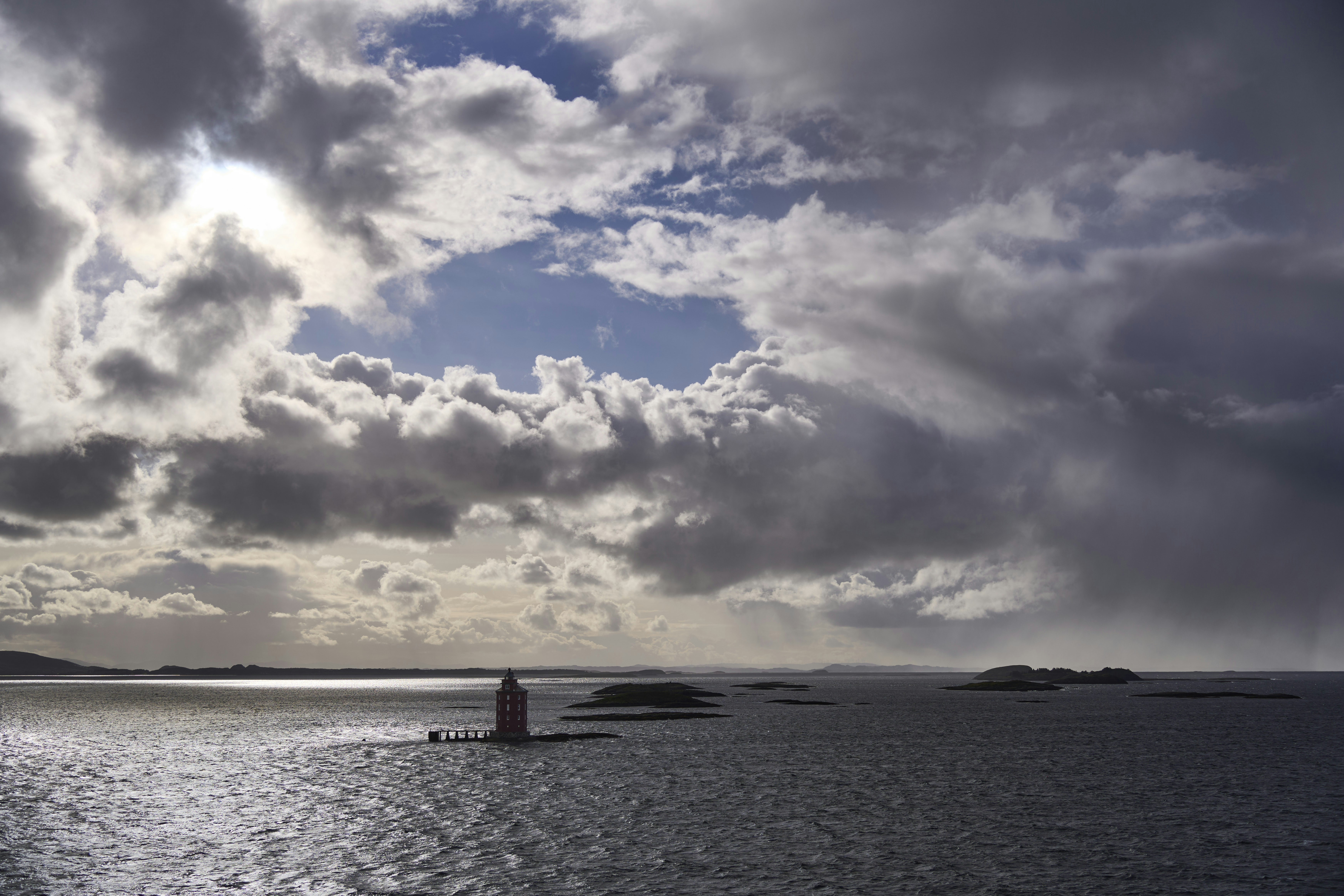 Lighthouse on a calm sea under dramatic clouds