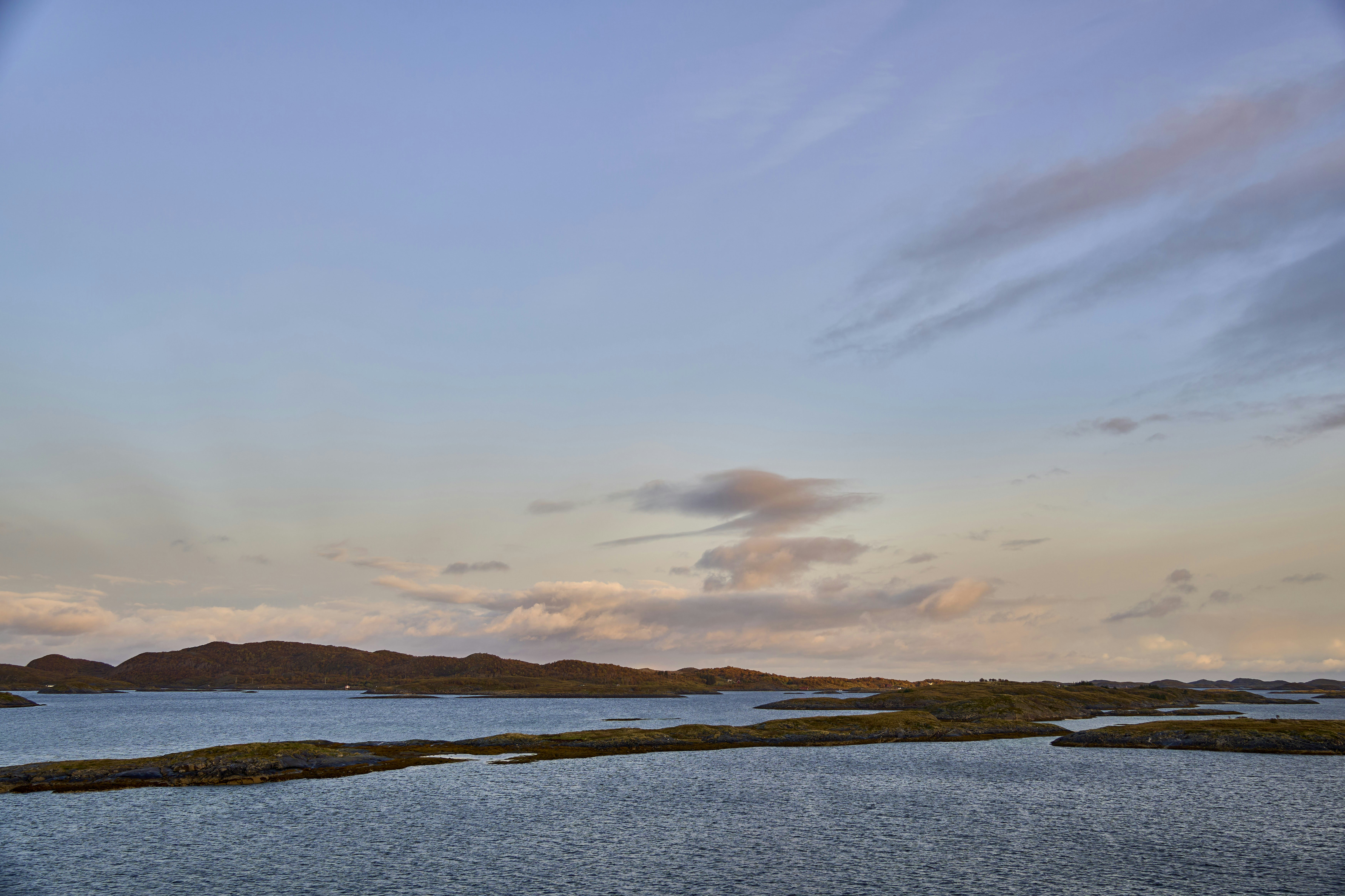 Scattered islands in tranquil water beneath a pastel sky.