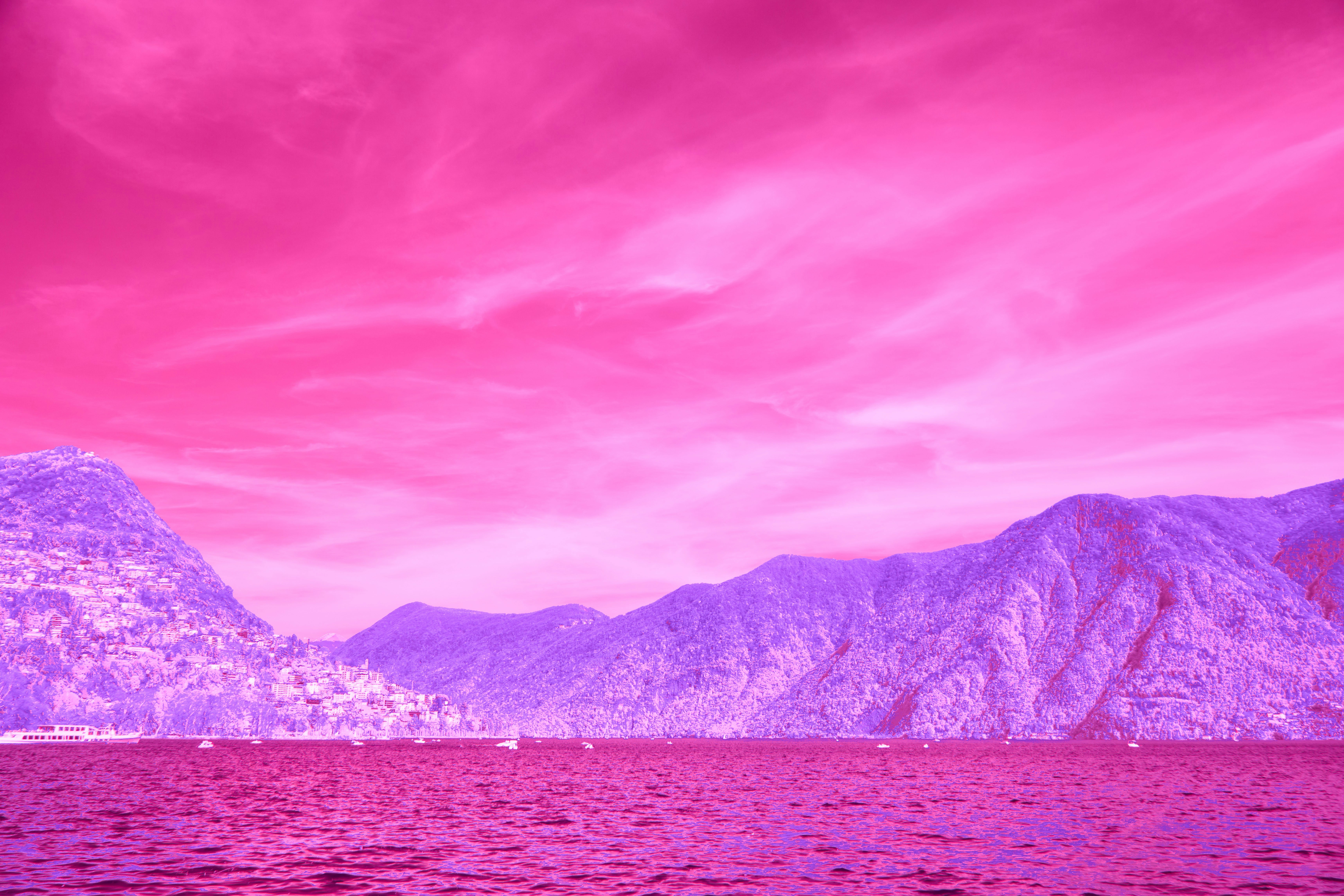 Surreal pink and purple sky above mountains and water.