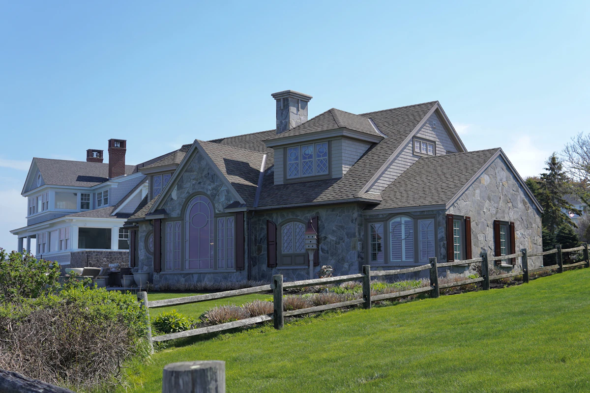 Stone shingle-style estate under a blue sky at 55 Palmiera Circle