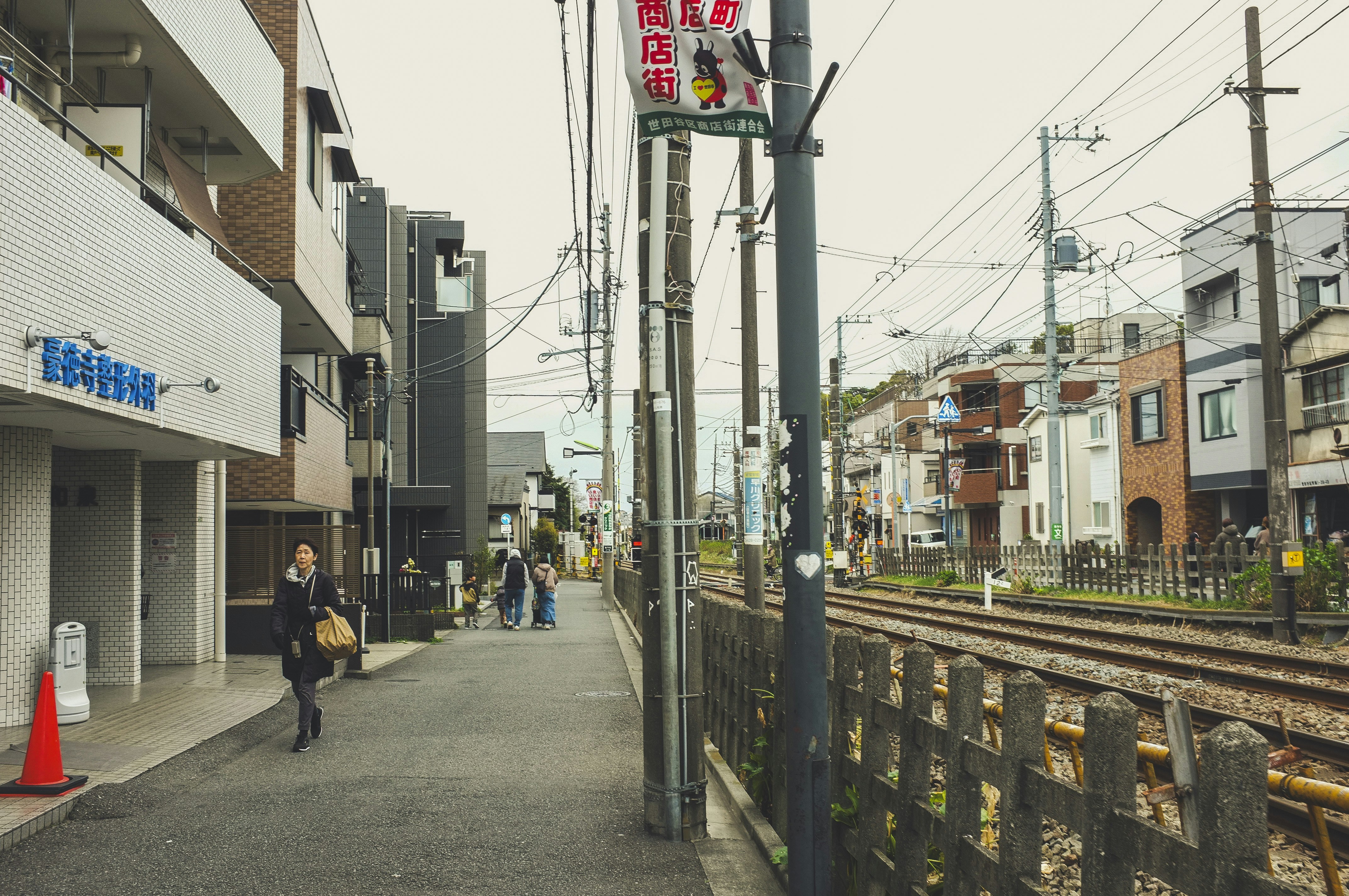 Woman walking on urban street next to train tracks.