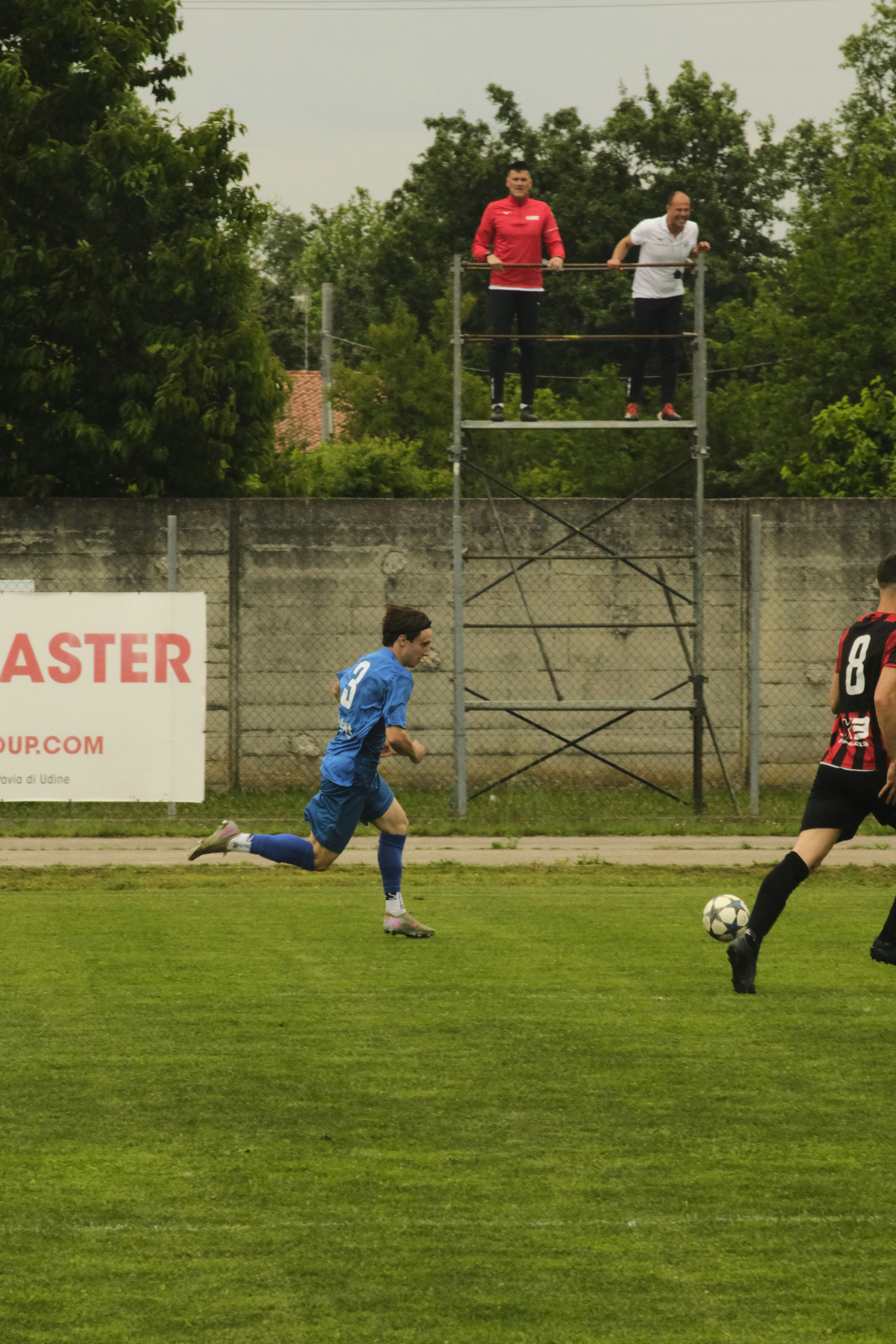 Soccer player running on field with spectators watching.