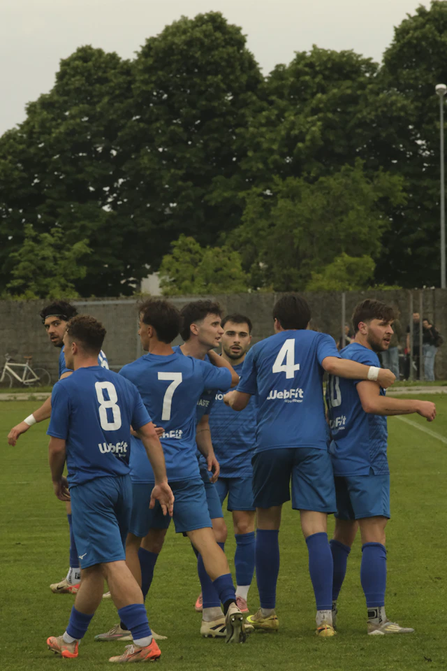 A blue-uniformed team huddle on the grass