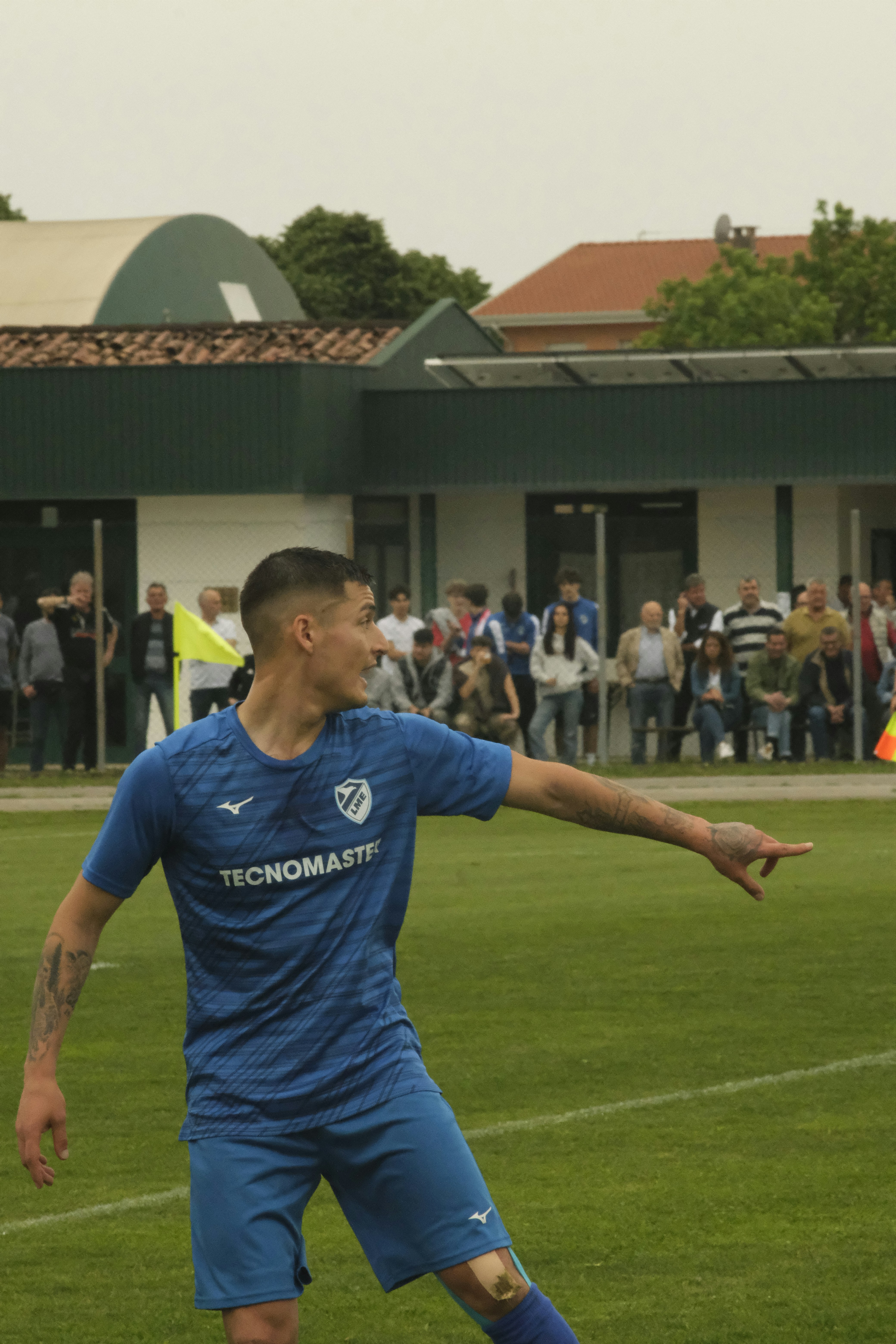 A male soccer player in blue points on the field.