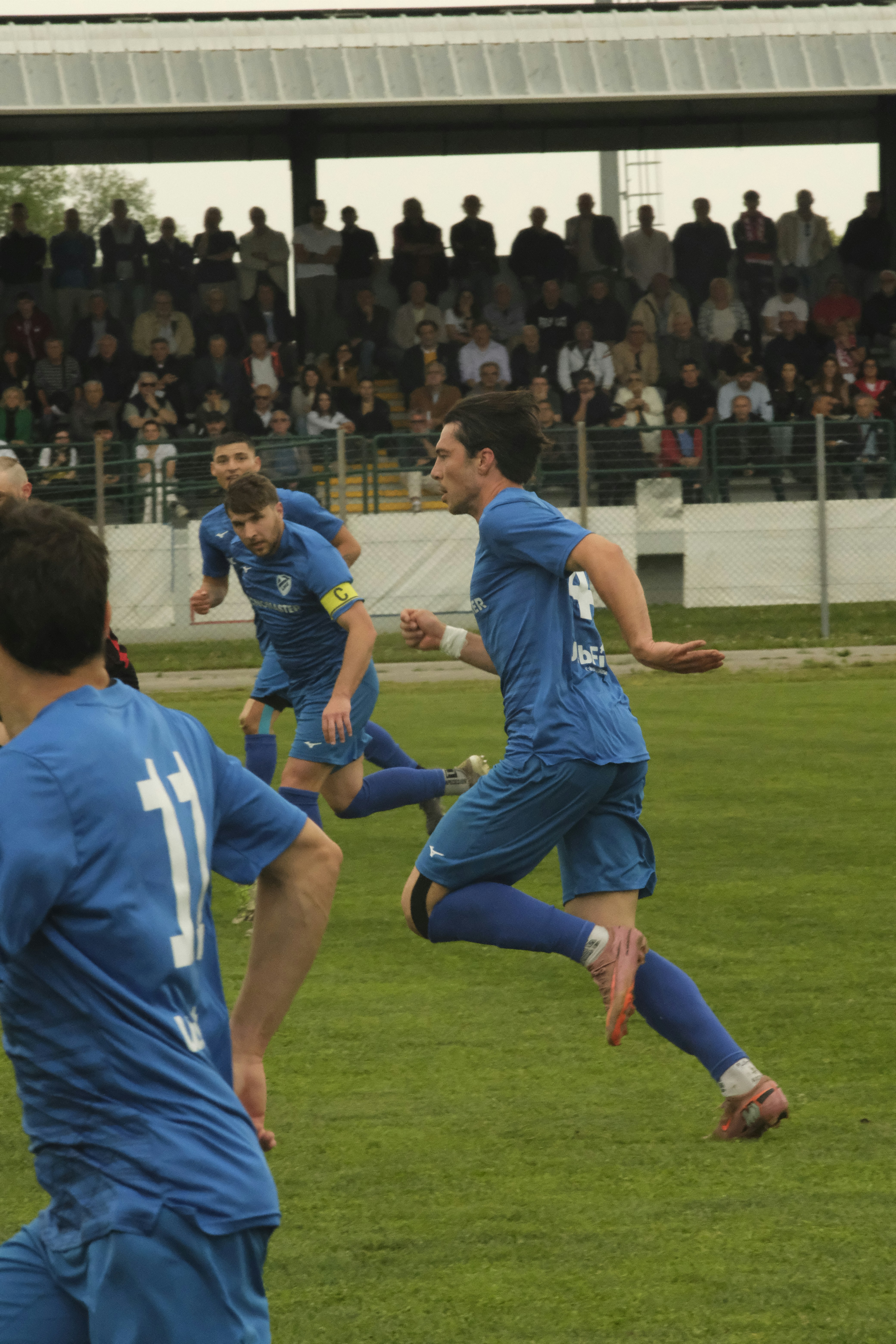 Des joueurs de football en uniforme bleu courant sur un terrain.