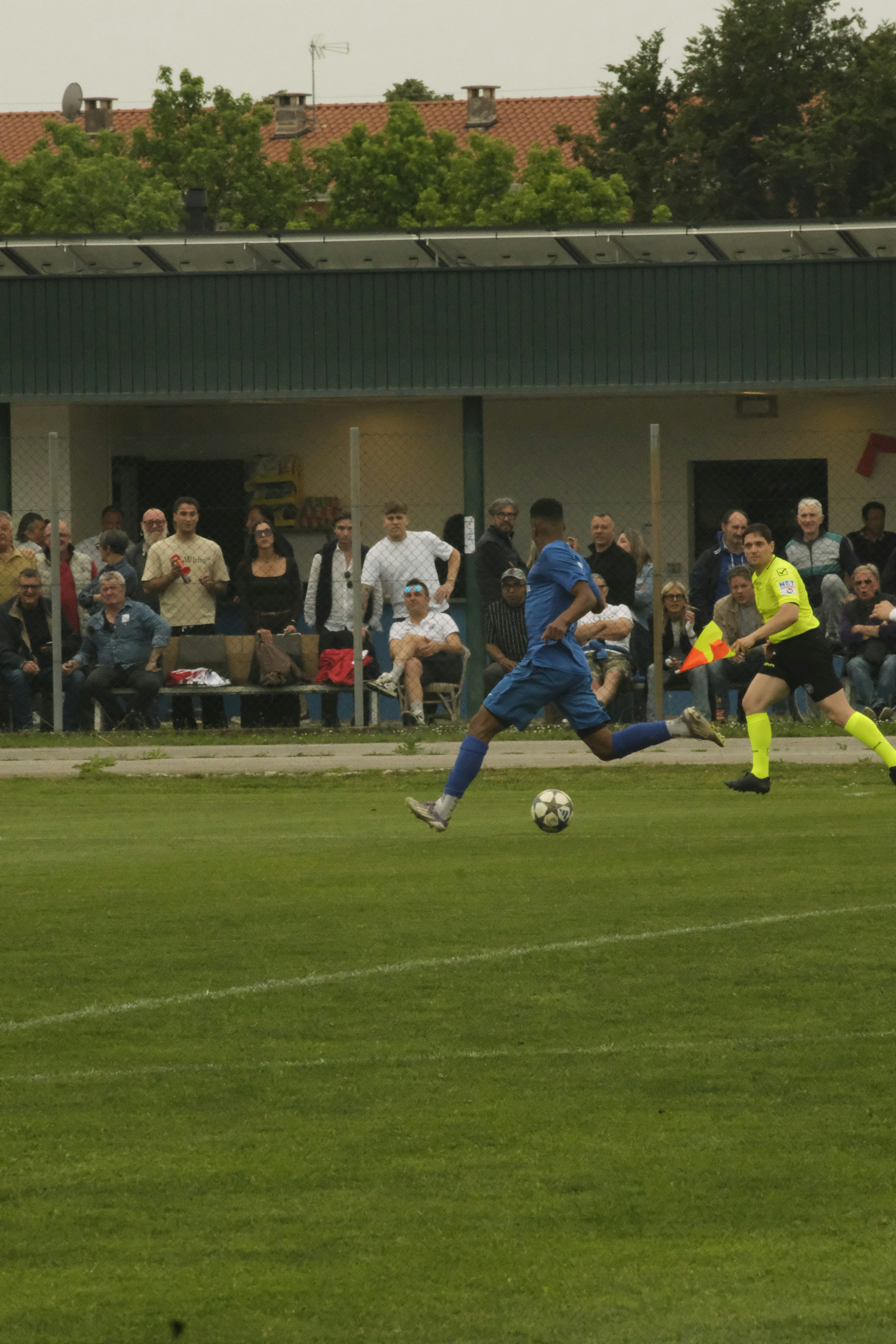 Soccer player in blue uniform kicking ball on green field.