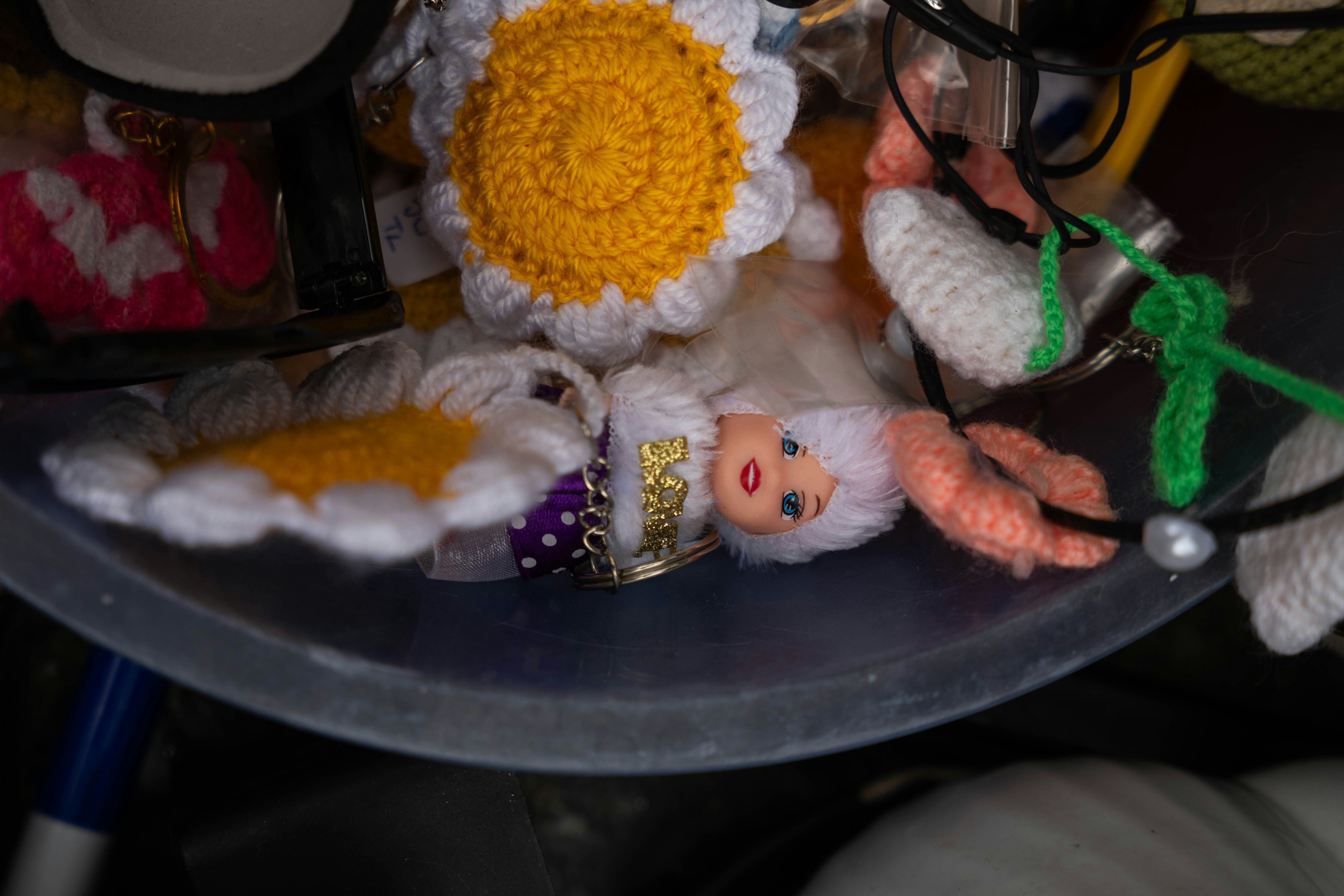 Crocheted daisy, doll head, and trinkets in a plastic bin.