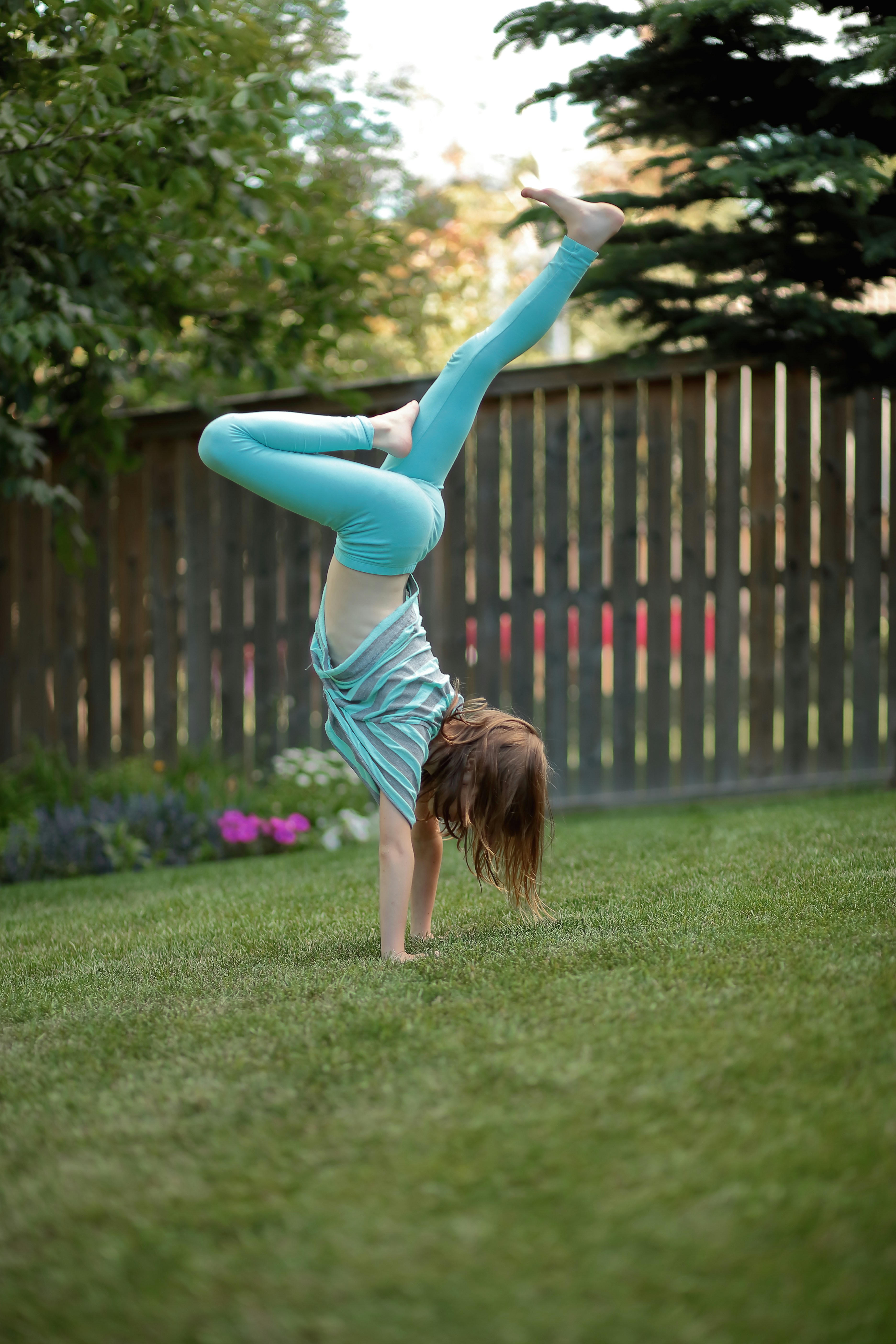 A young girl does a handstand on the grass.