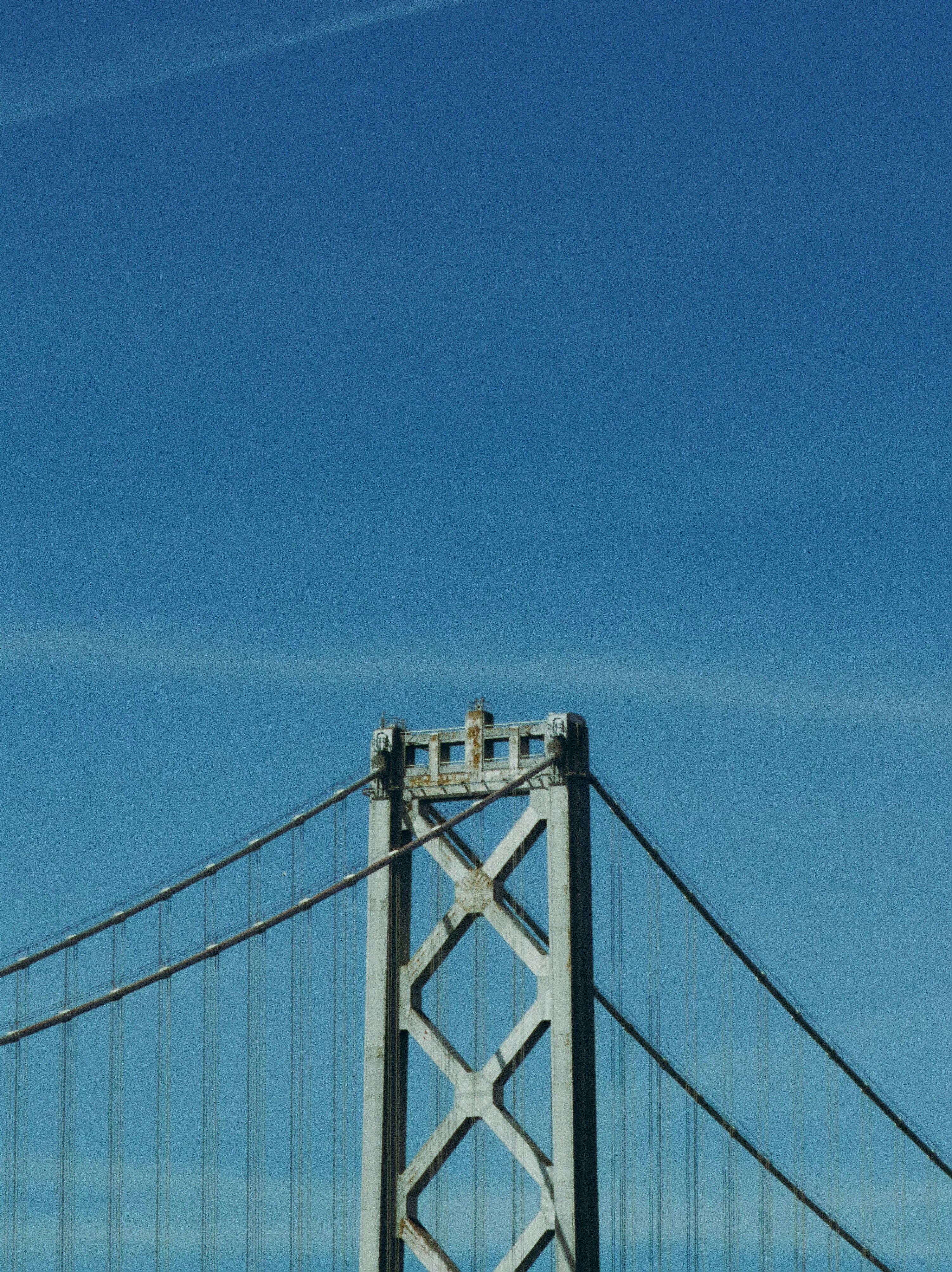 A bridge tower and cables against a clear blue sky.