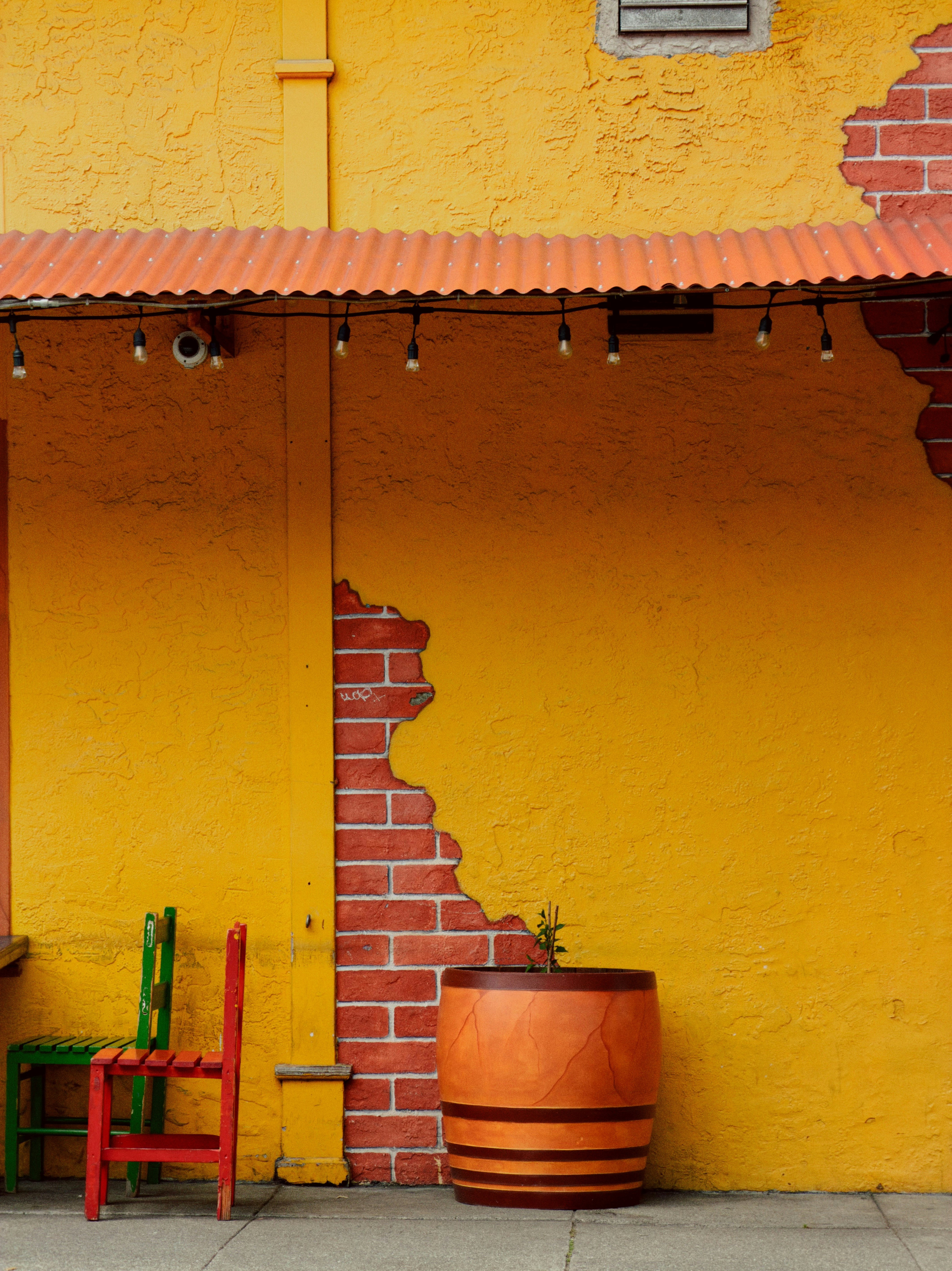 Yellow wall with exposed brick and colorful chairs