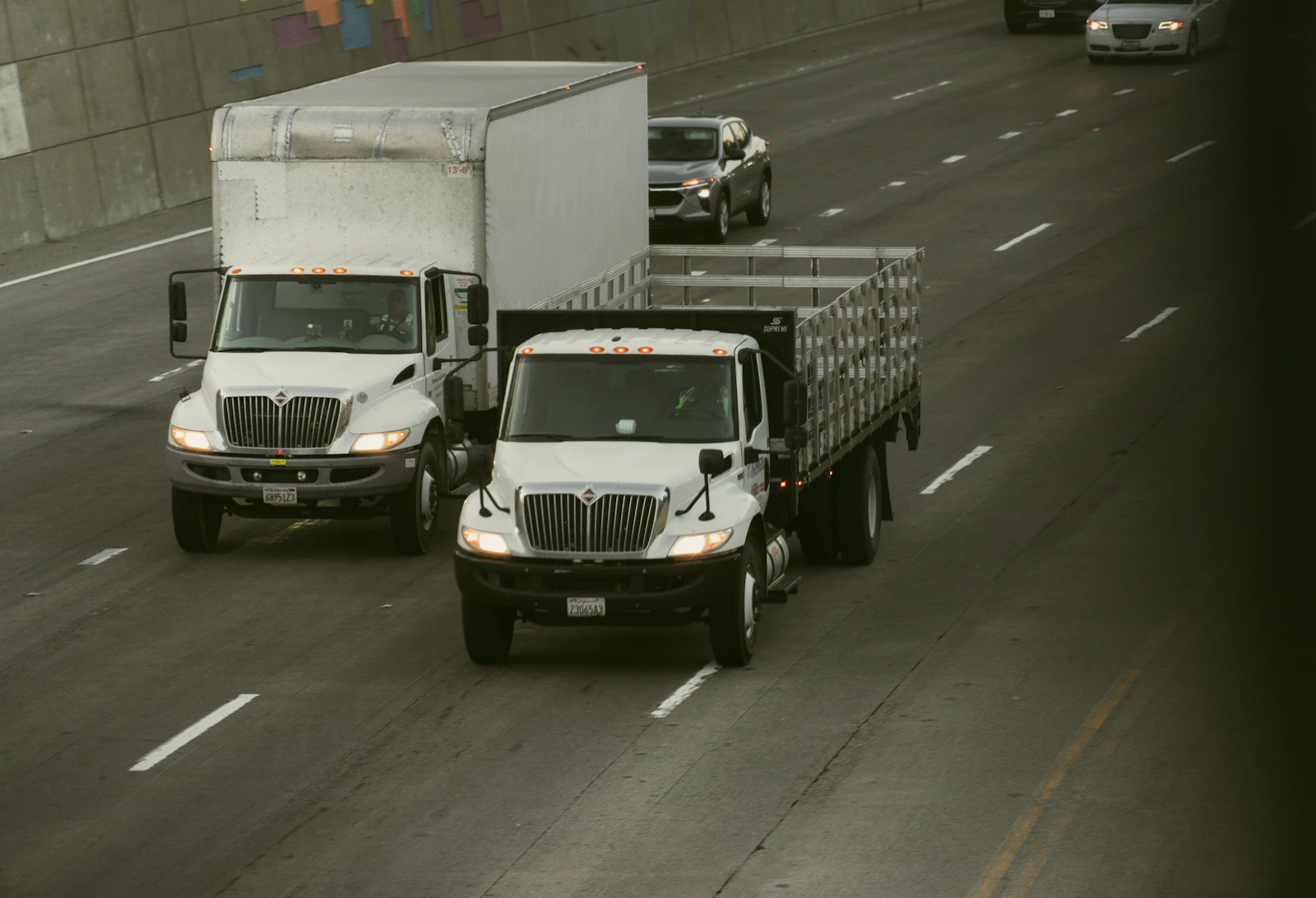Two white trucks traveling on a highway