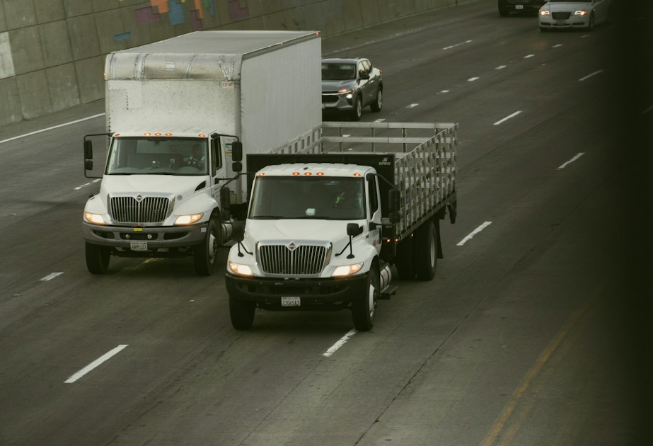 Two white trucks driving on a highway