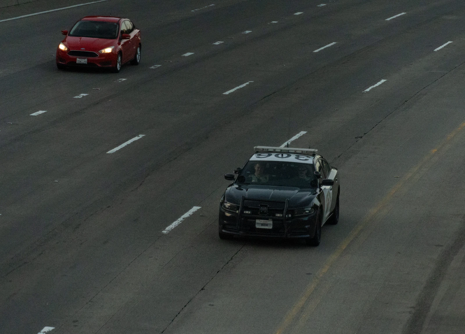 patrol car and a red sedan on a multi lane highway