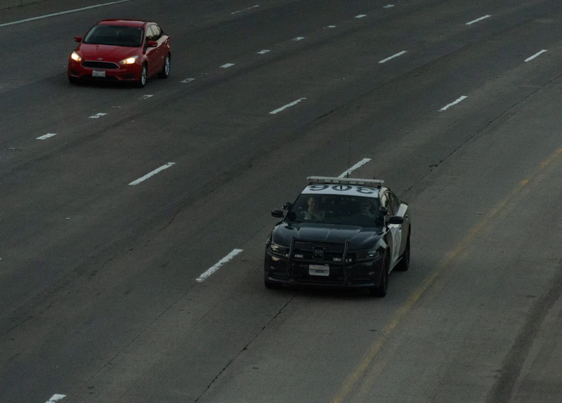 Patrol car and a red sedan on a multi lane highway