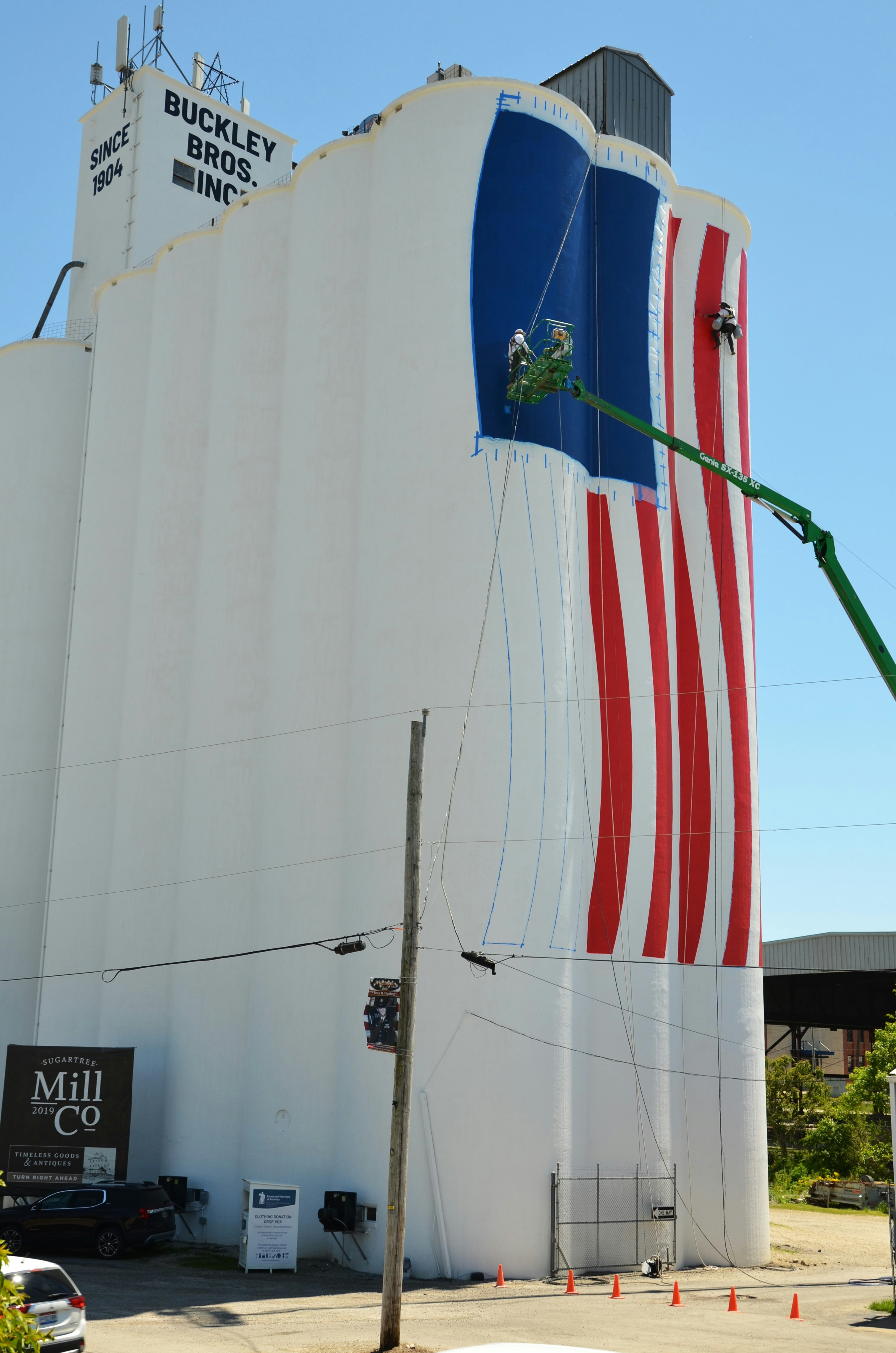Los trabajadores pintan una gran bandera americana en un silo blanco.