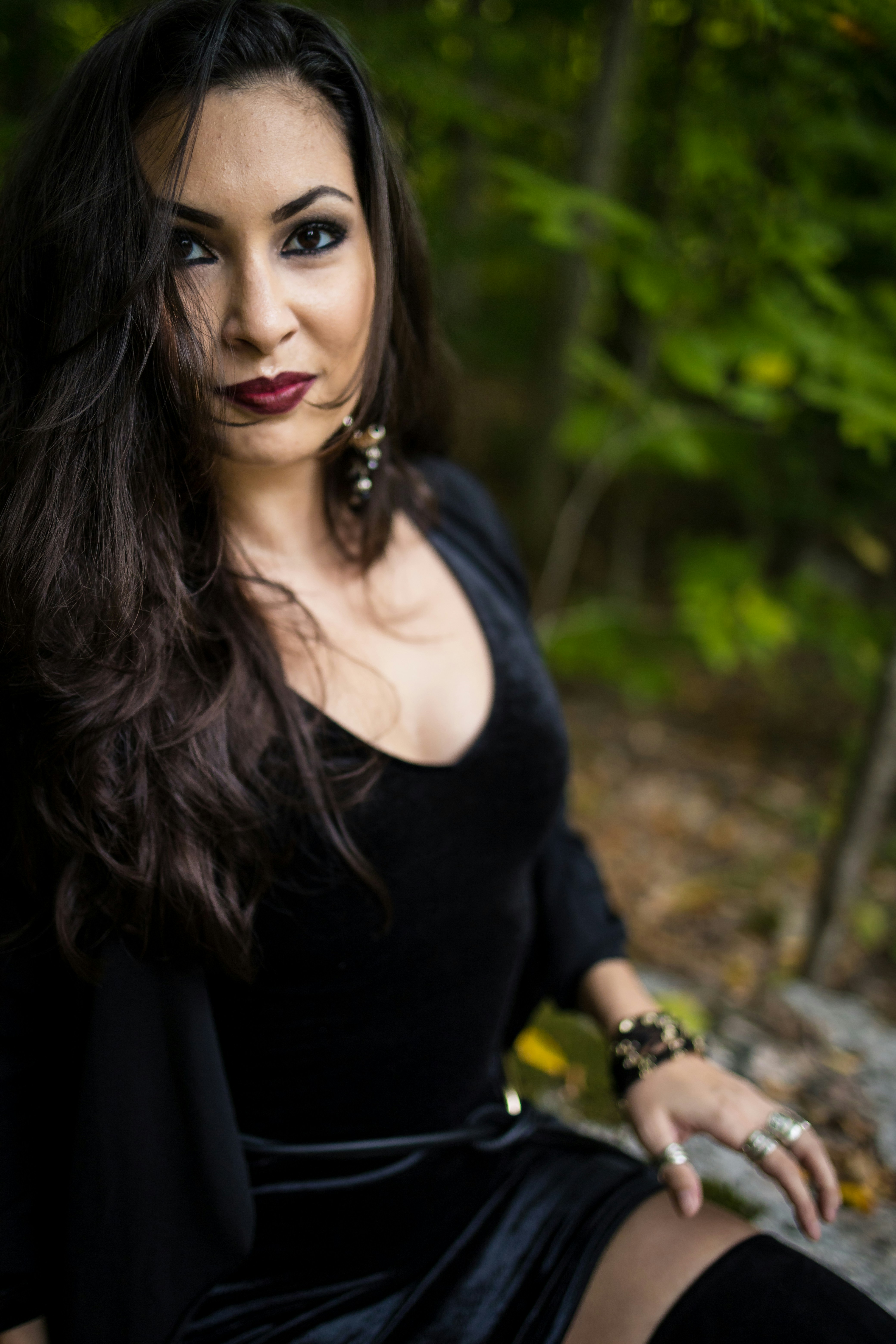 A woman in a black dress sits outdoors.