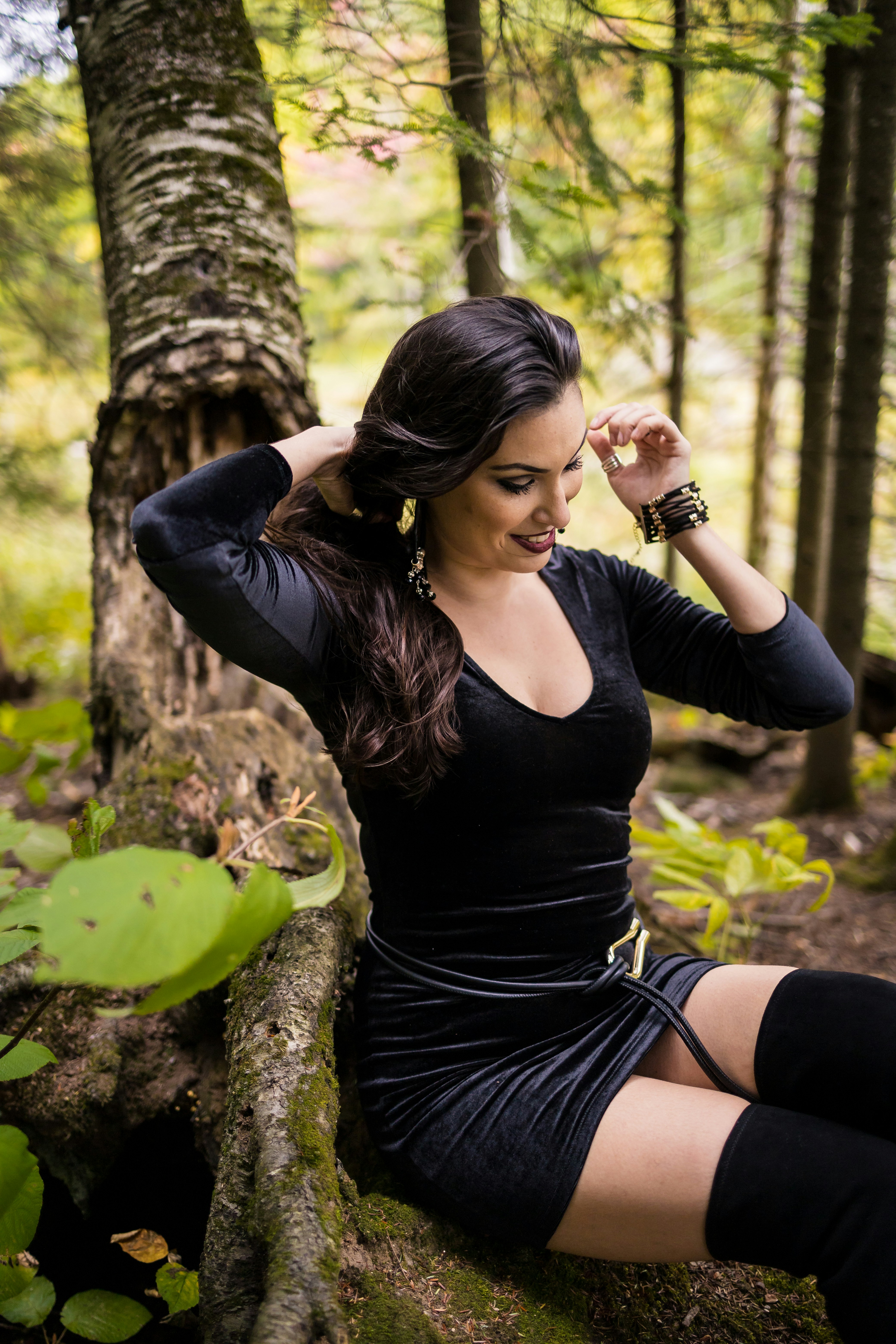 Mujer vestida de negro sentada junto a un árbol
