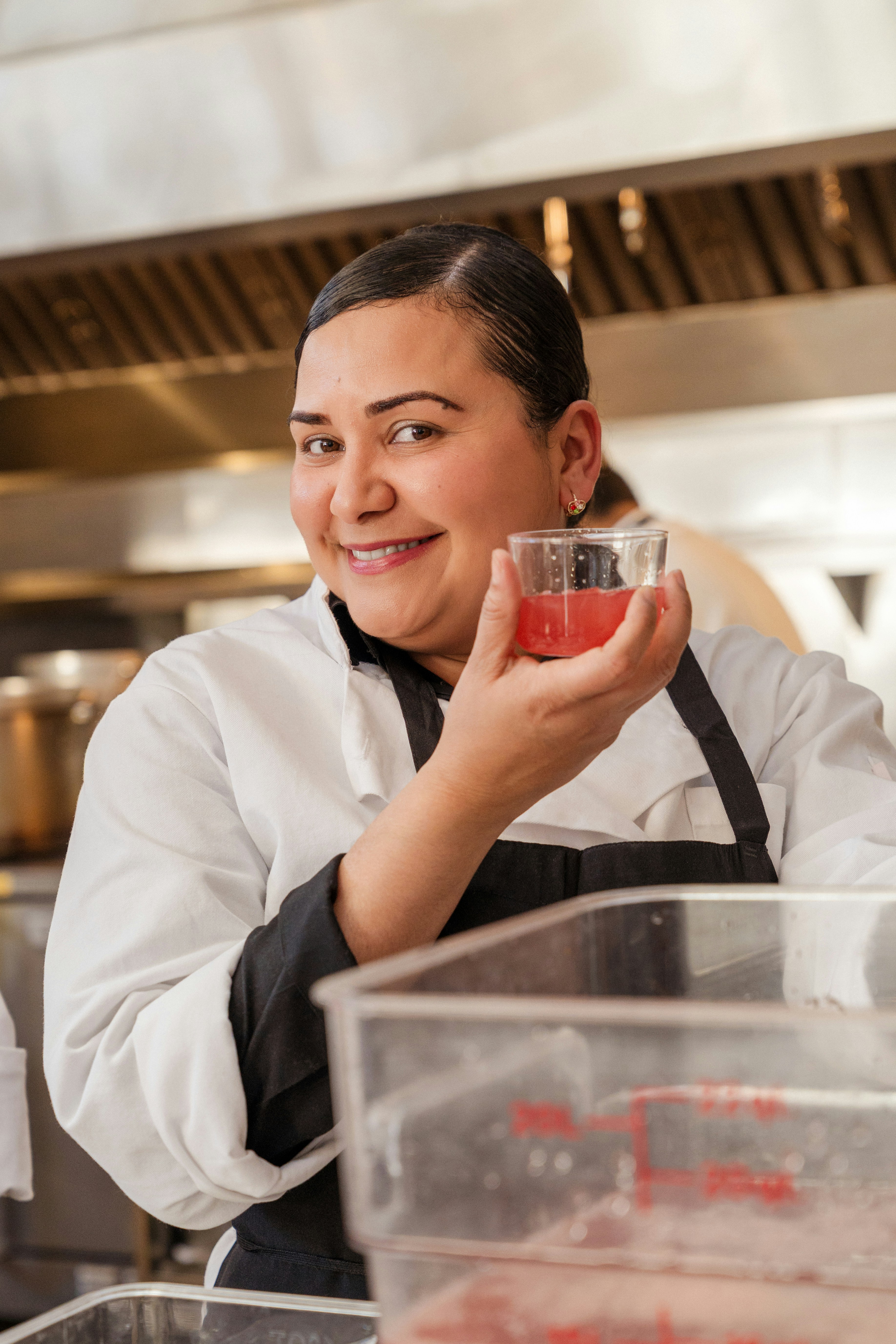 Uno chef sorridente tiene in cucina un liquido rosa.