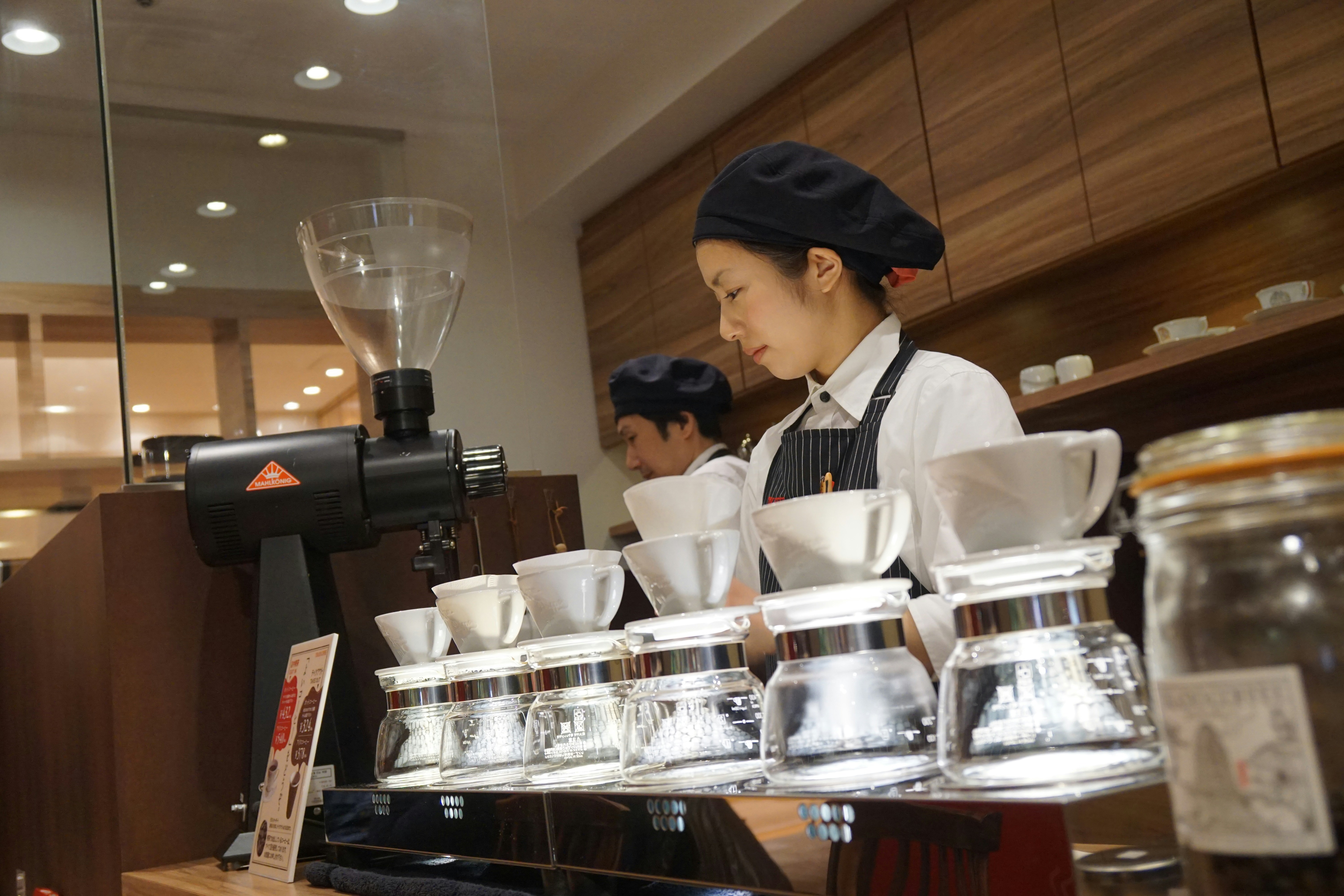 A barista preparing multiple pour-over coffees in a cafe.