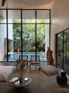 Modern living room with pool view and lush greenery.