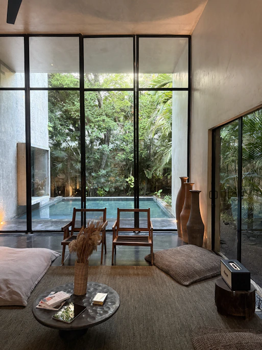 Modern living room with pool view and lush greenery.