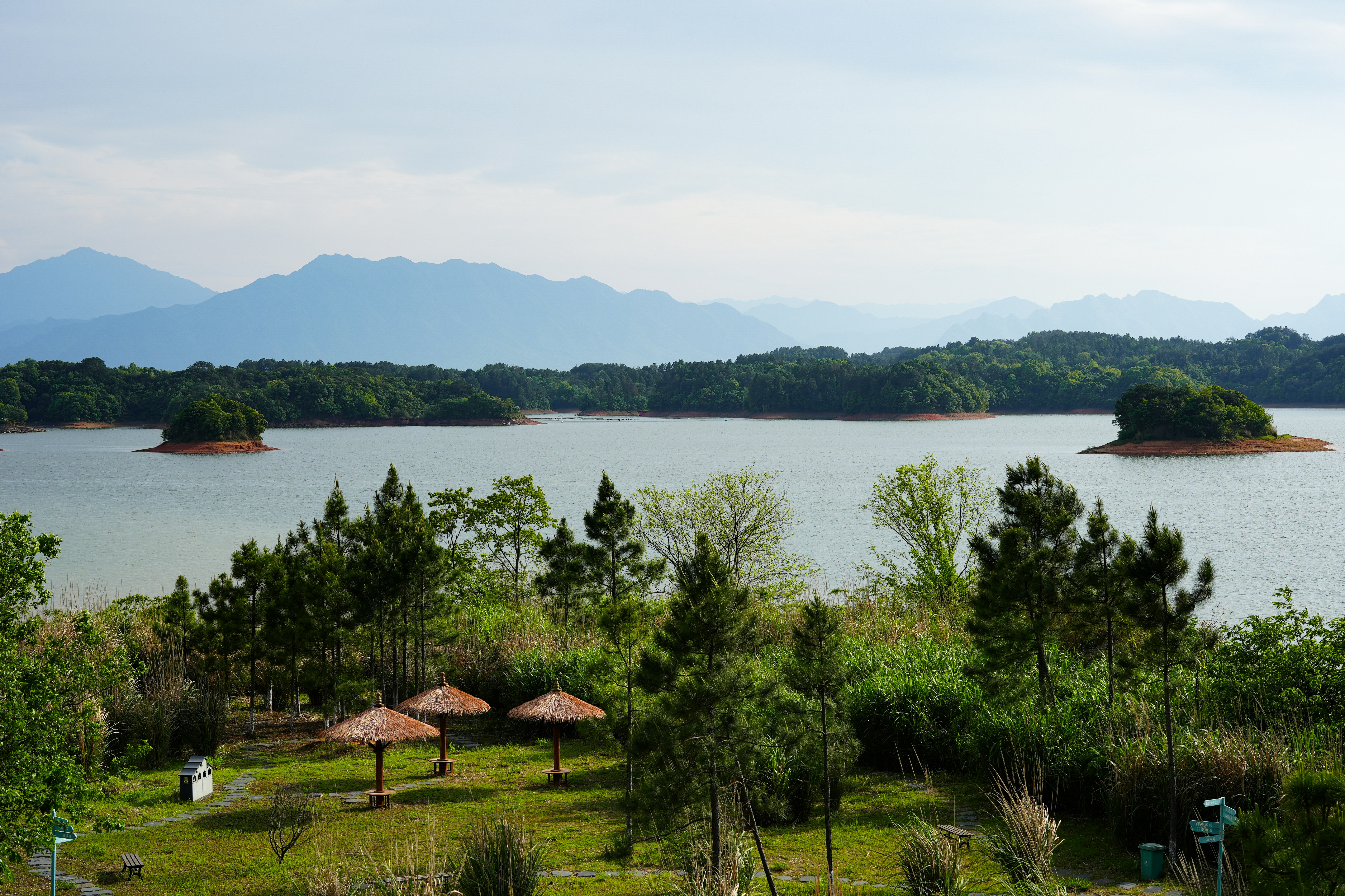 Lago com ilhas e colinas arborizadas sob um céu enevoado