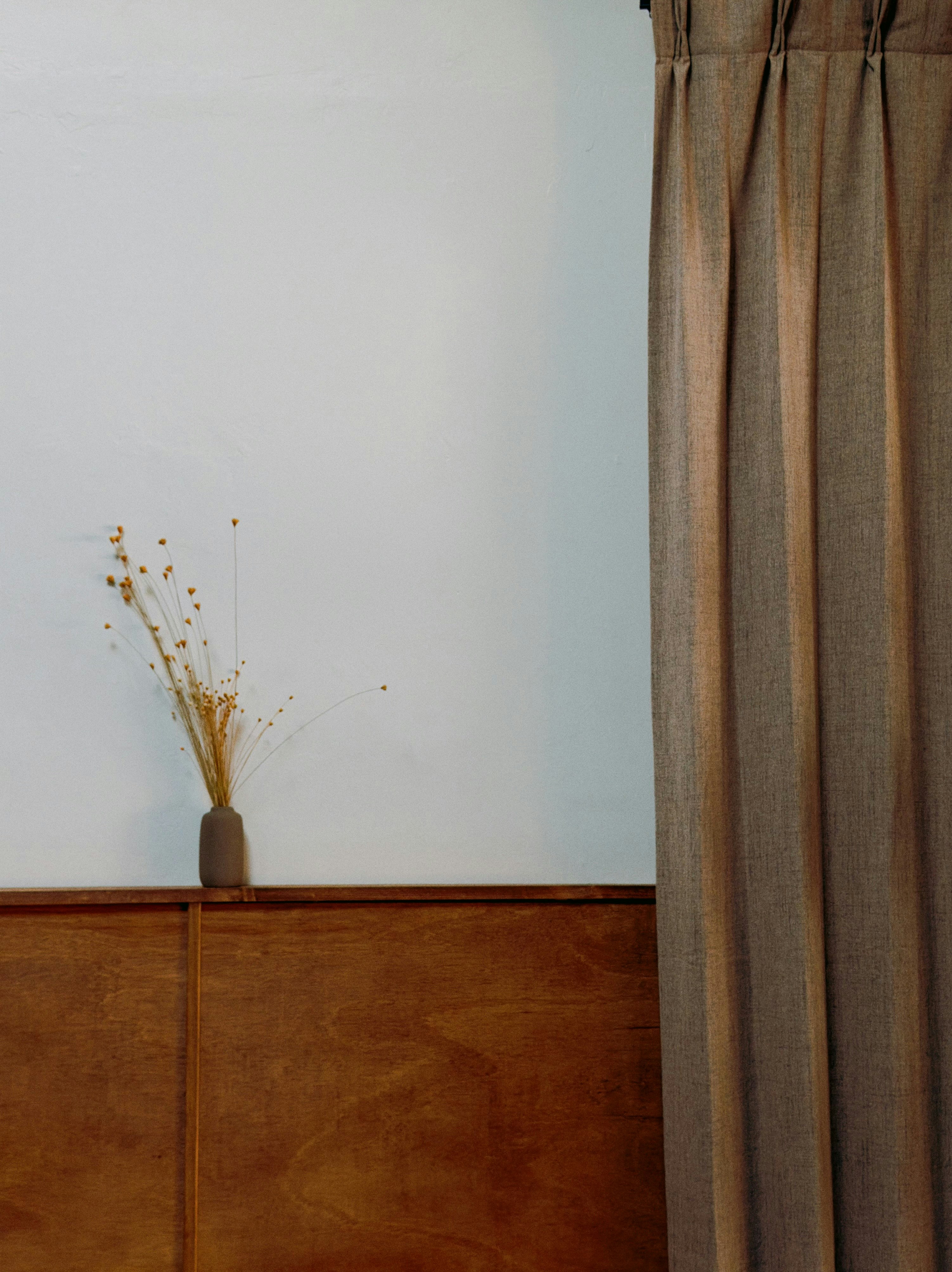 A small vase with dried flowers on a wooden surface.