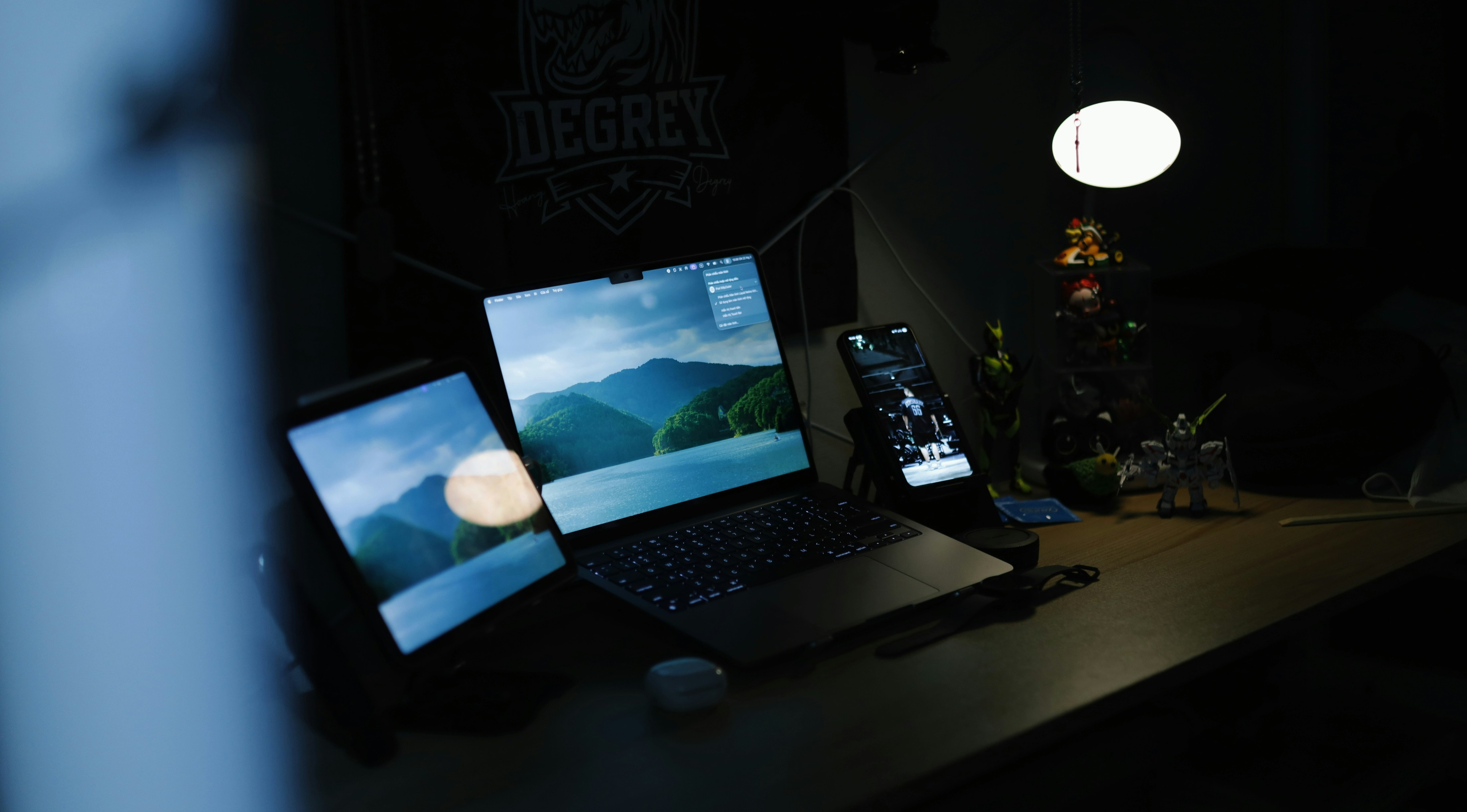 Laptop, tablet, and phone on a desk at night.