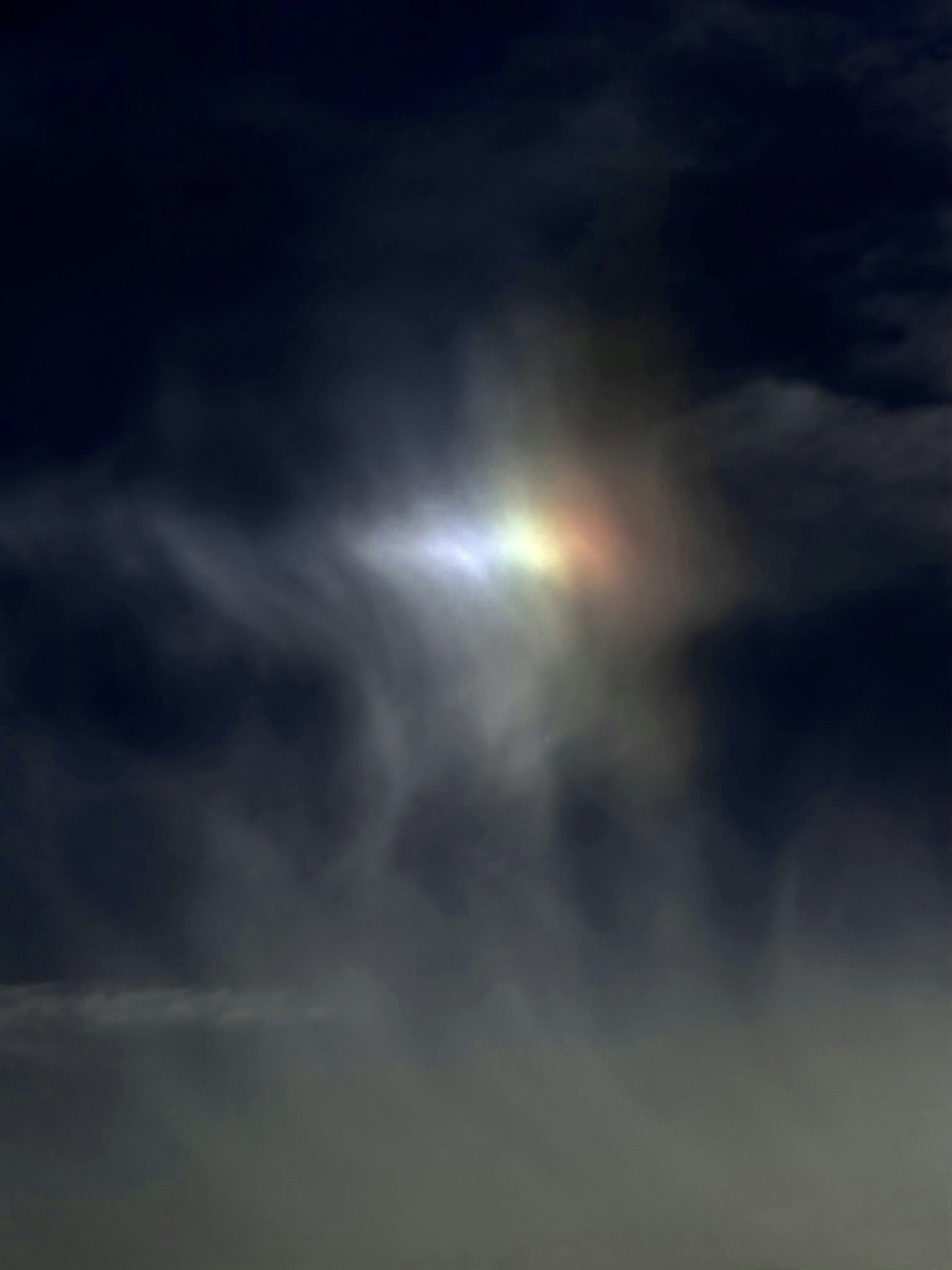 Awan warna-warni bersinar dengan cahaya warna-warni di langit yang gelap.