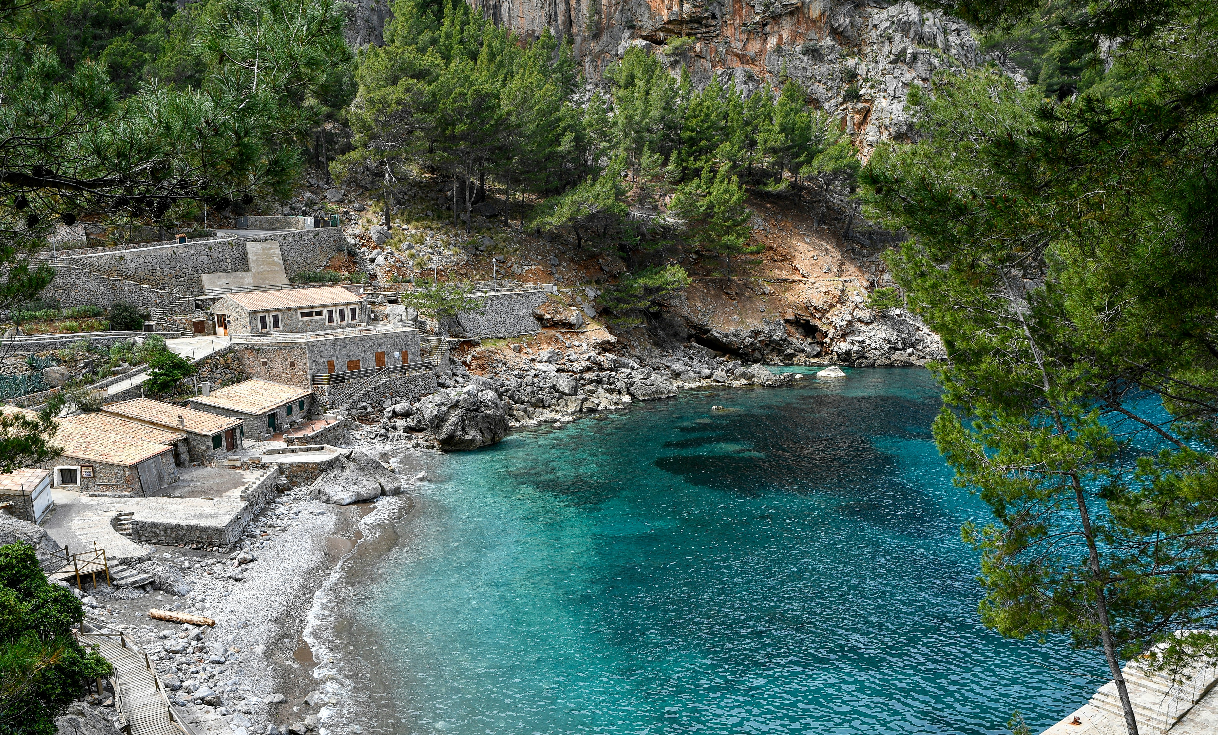 Rocky bay with turquoise water, beach, and stone buildings