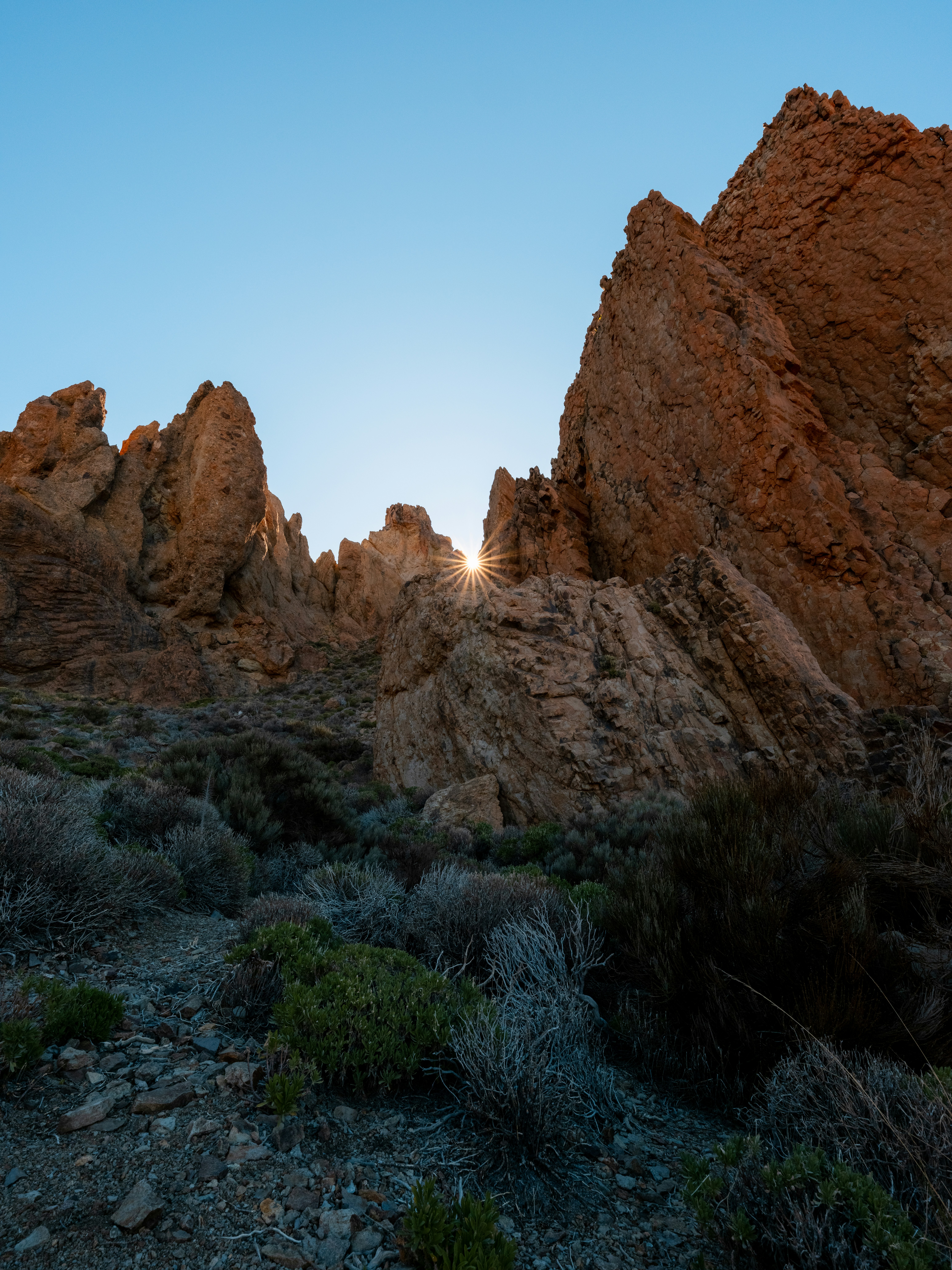 Sunlight peeking through rocky mountain peaks at sunrise