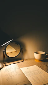 An open book, a cup of coffee, and a mirror.