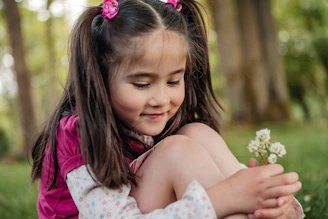 A young girl holding a small white flower