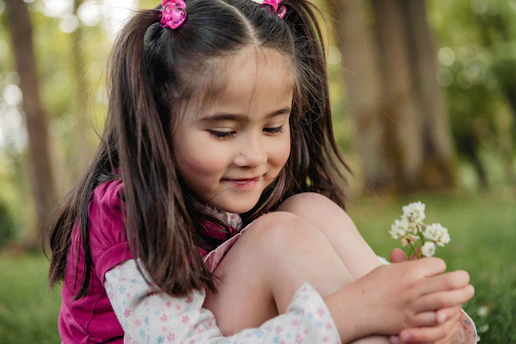 A young girl holding a small white flower