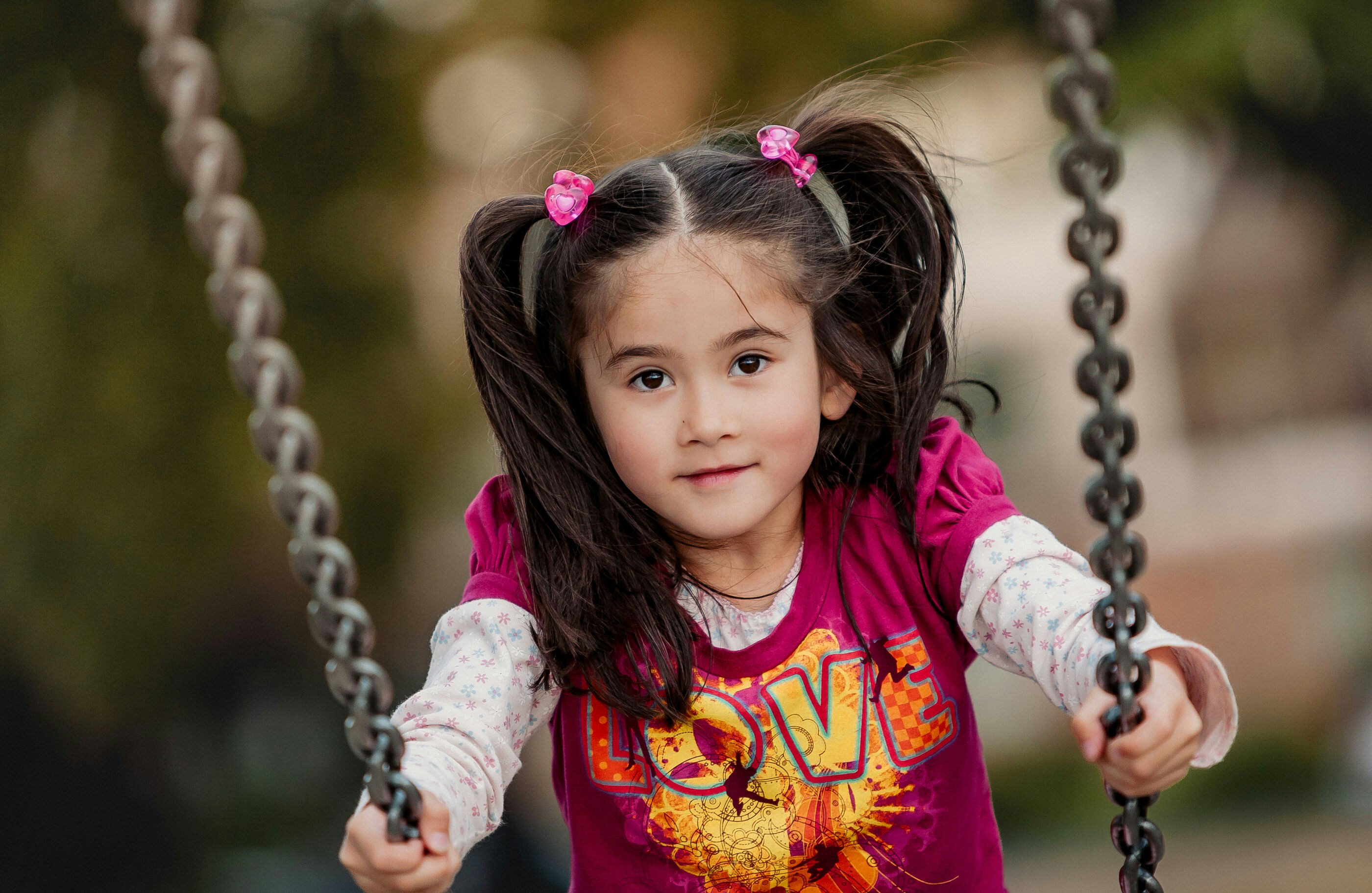 A young girl with pigtails on a swing