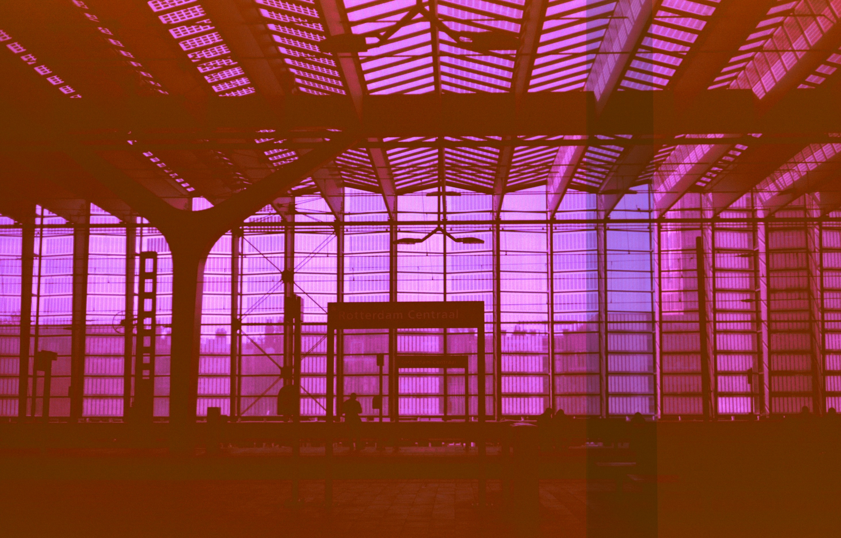 Modern building interior with glass roof and purple-orange color overlay.