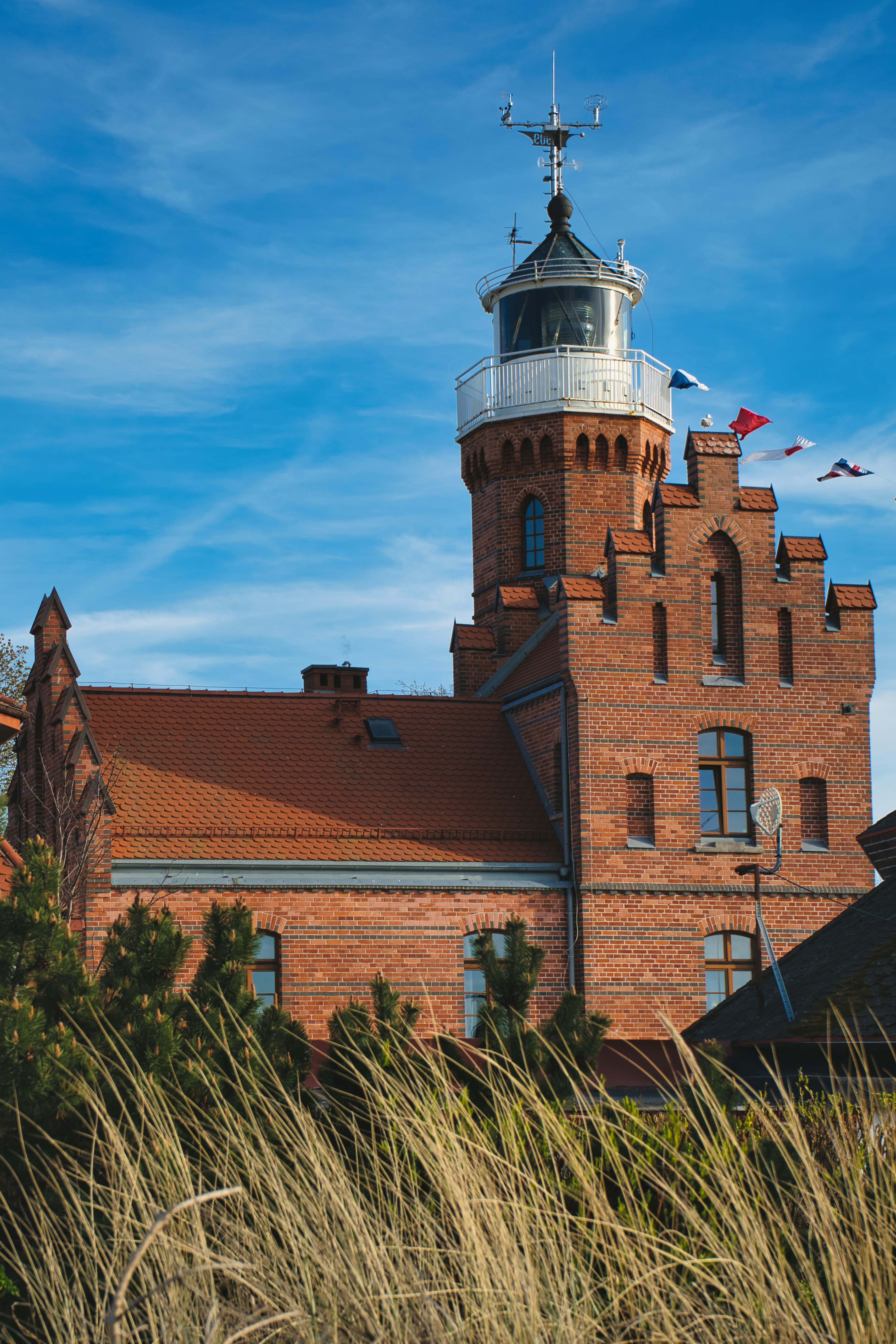 Red brick lighthouse under a bright blue sky.